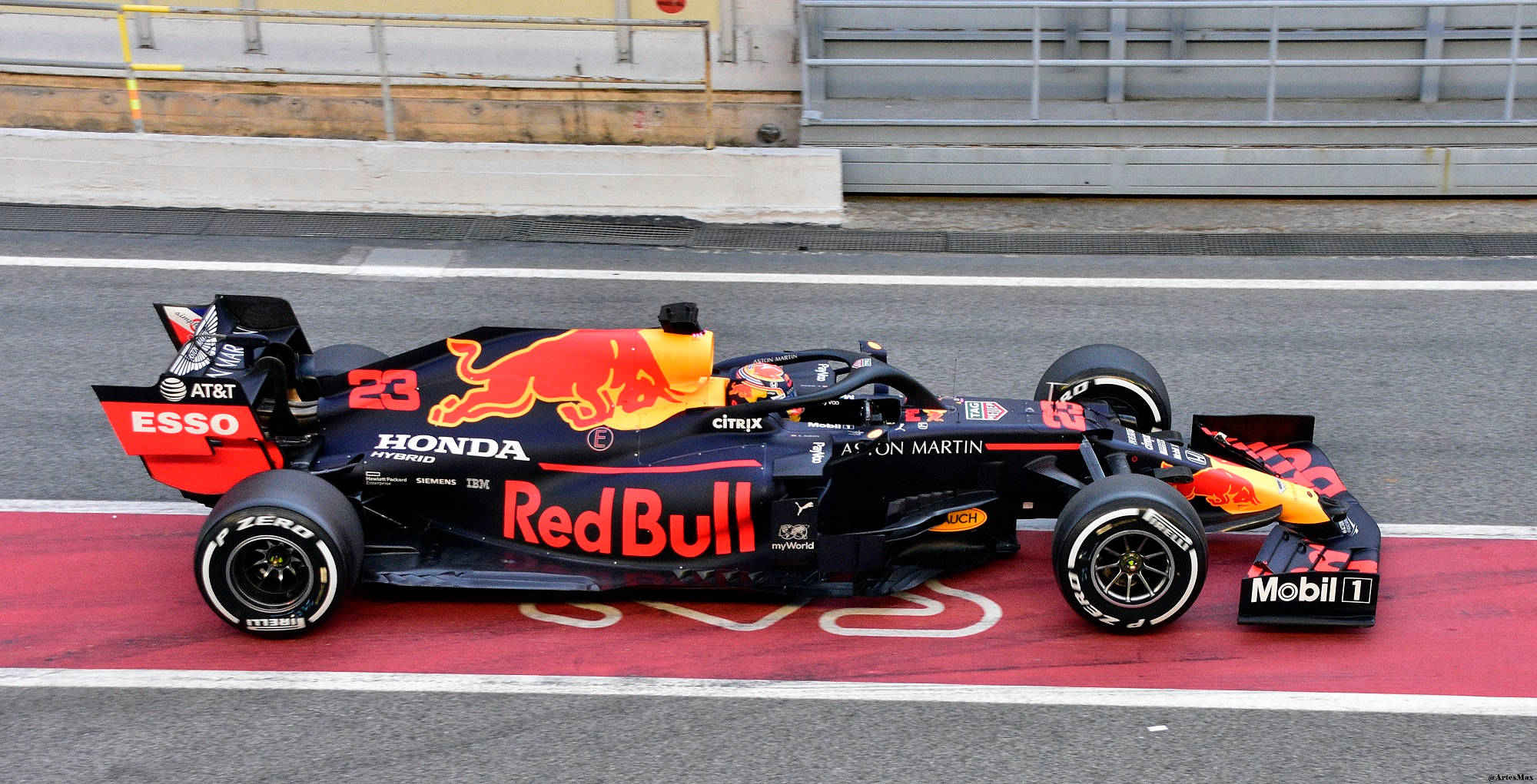 F1 桌布 壁紙 — 一輛流線型的紅牛車隊一級方程式賽車，編號23，在紅白相間的賽道邊緣疾馳。