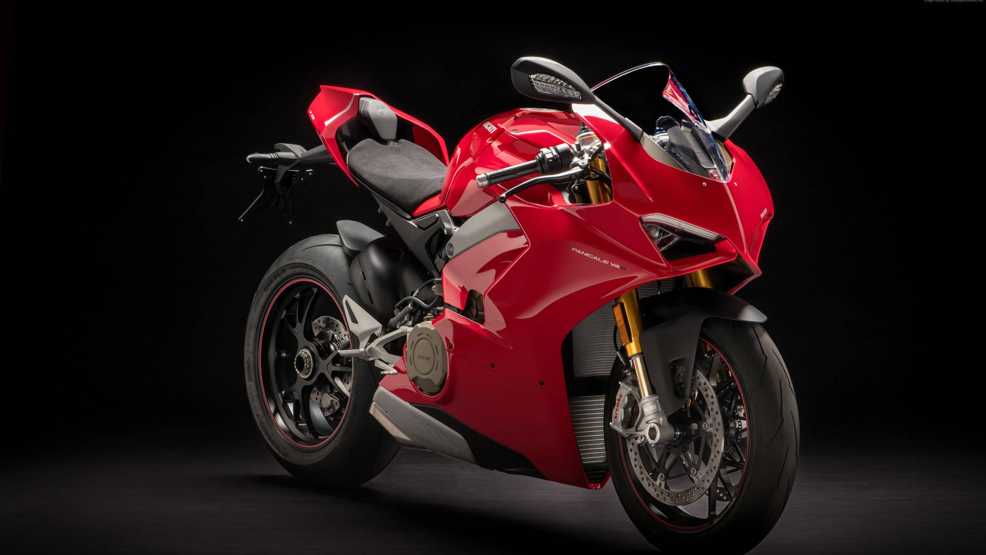 杜卡迪 桌布 壁紙 — 一輛流線型的紅色Ducati Panigale V4運動摩托車在純黑色背景下於攝影棚燈光下閃耀。