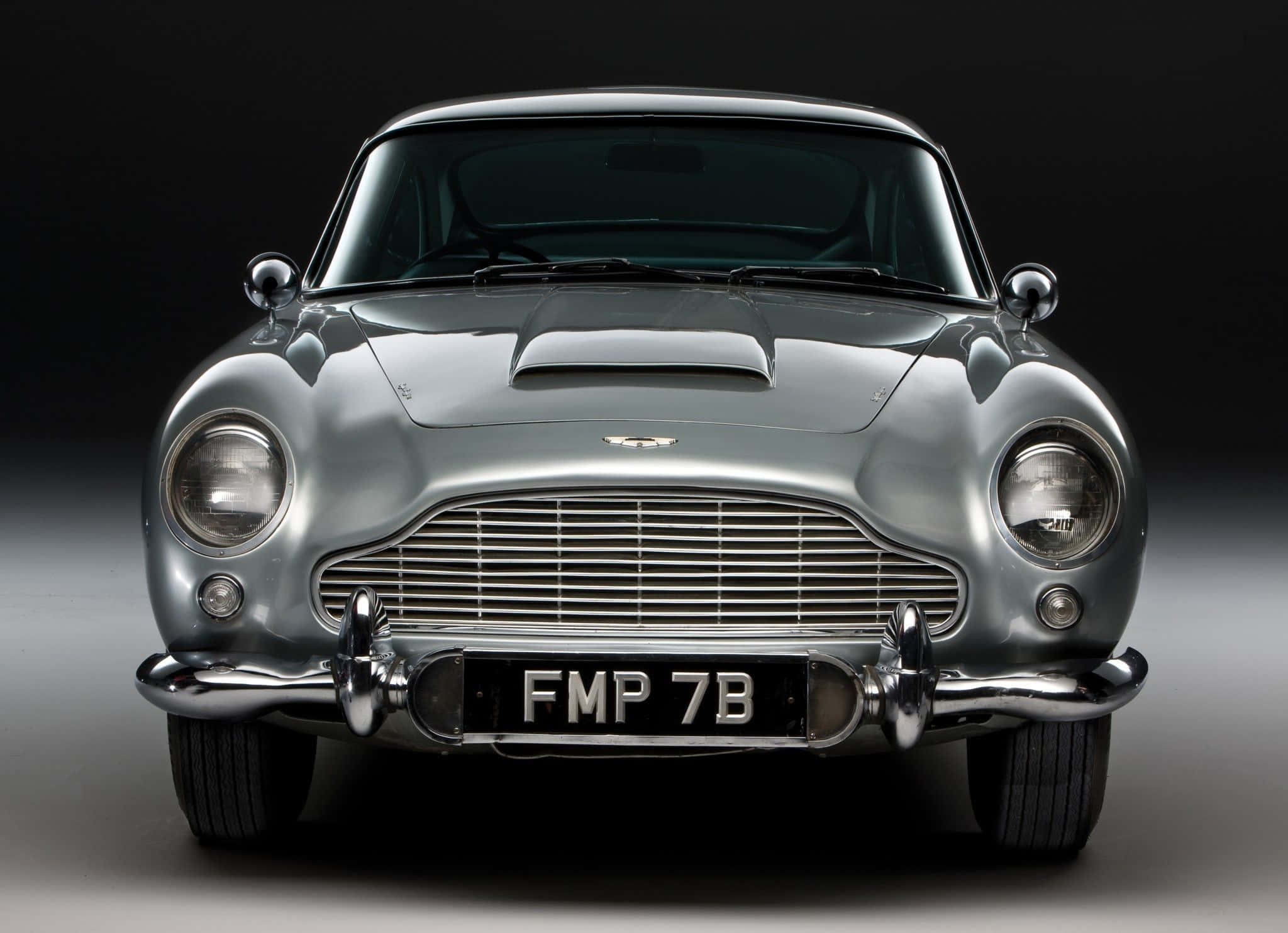 Aston Martin Db5 桌布 壁紙 — 一輛流線型的銀色Aston Martin DB5在攝影棚燈光下閃耀，帶有鍍鉻飾邊和標誌性格柵。
