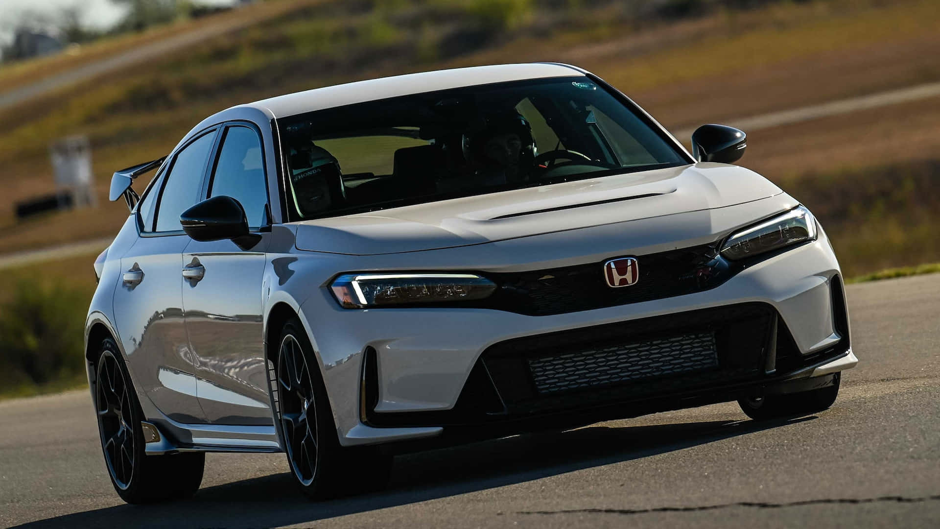 Honda Civic 桌布 壁紙 — 一輛流線型的銀色本田Civic Type R在陽光照耀的柏油路上奔馳，背景是模糊的草坡。