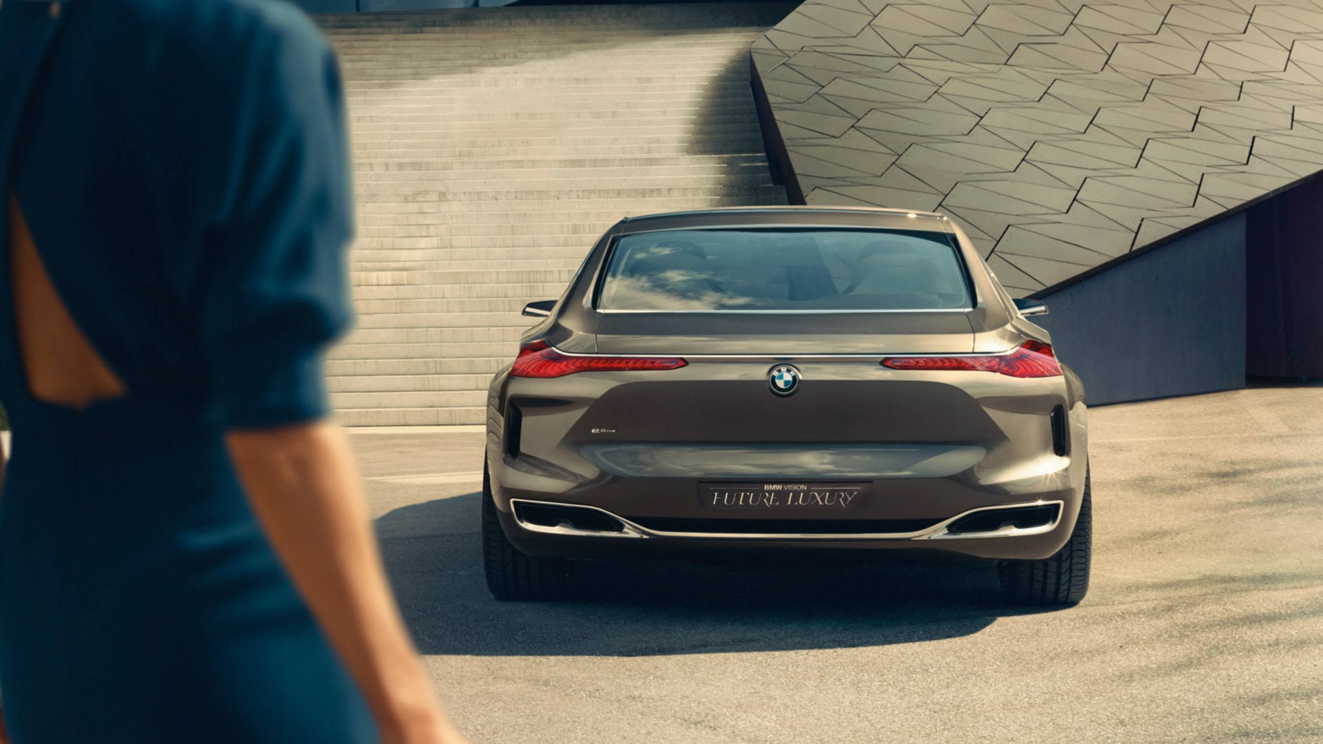 Luxury 桌布 壁紙 — 一輛流線型的青銅色BMW概念車停放在現代幾何建築前，一位身穿藍色連衣裙的女性走過。