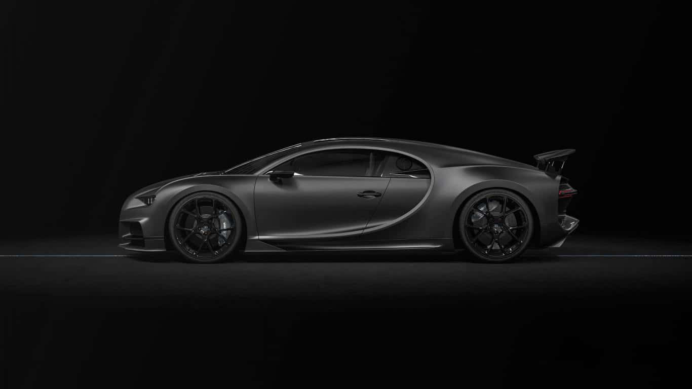霧面黑色 桌布 壁紙 — 一輛流線型磨砂灰色Bugatti Chiron跑車在強烈的黑色工作室背景下，以戲劇性的聚光燈側面滑行。