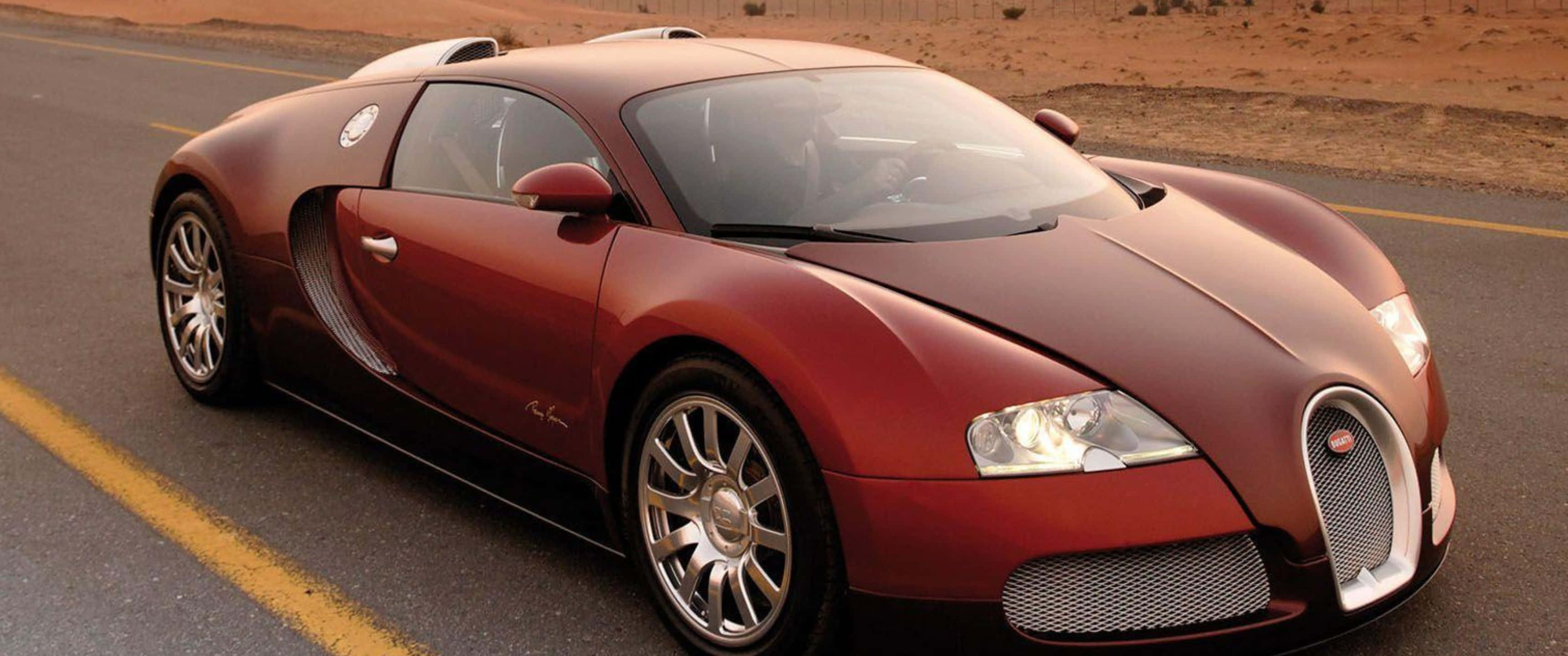 3440x1440p Bugatti 桌布 壁紙 — 一輛流線型紅色Bugatti Veyron在溫暖的金色光線下沿沙漠公路飛馳。