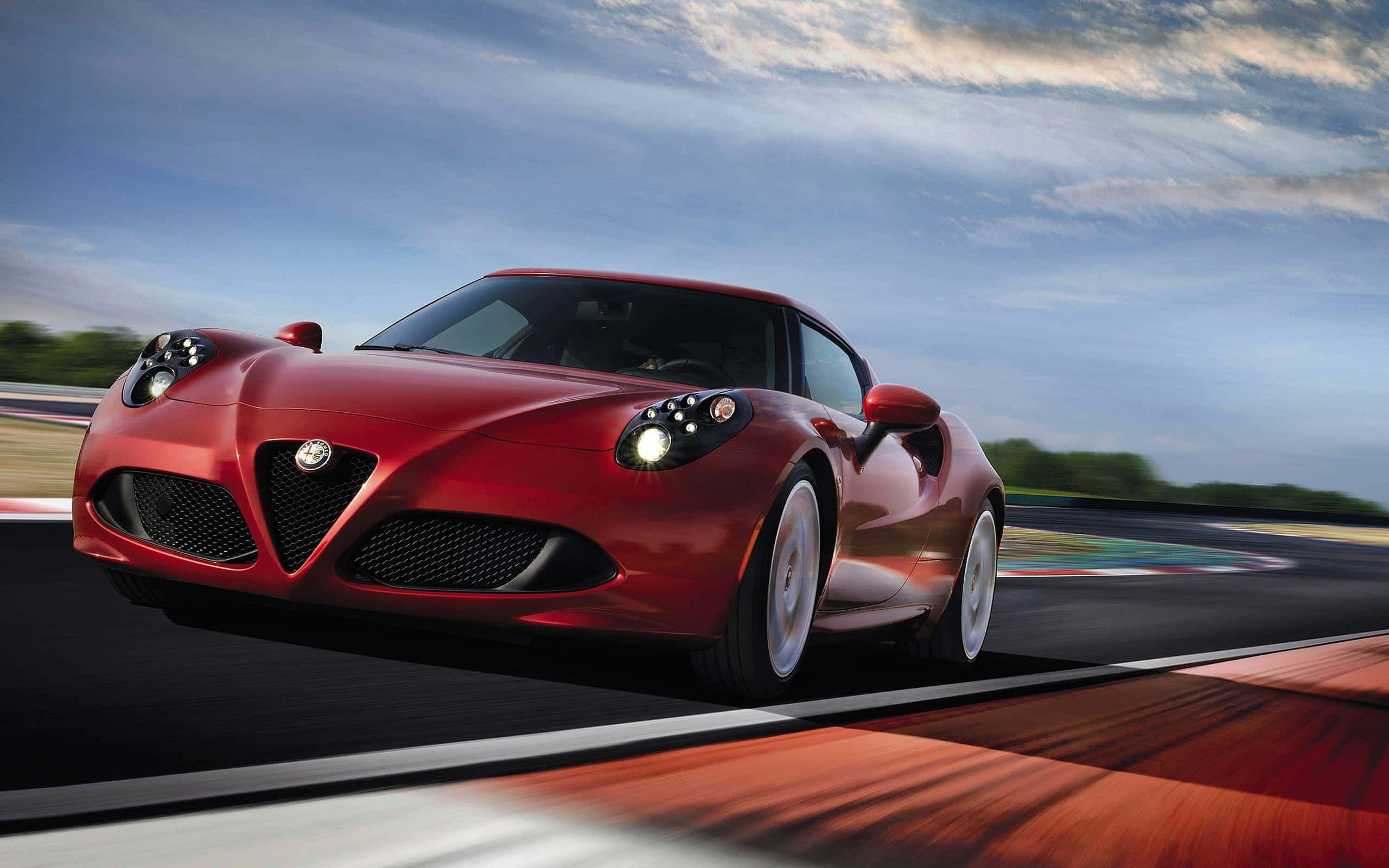 Alfa Romeo 4c 桌布 壁紙 — 一輛流線型紅色愛快羅密歐跑車在動感天空下，伴隨動態模糊效果，沿賽道疾馳。