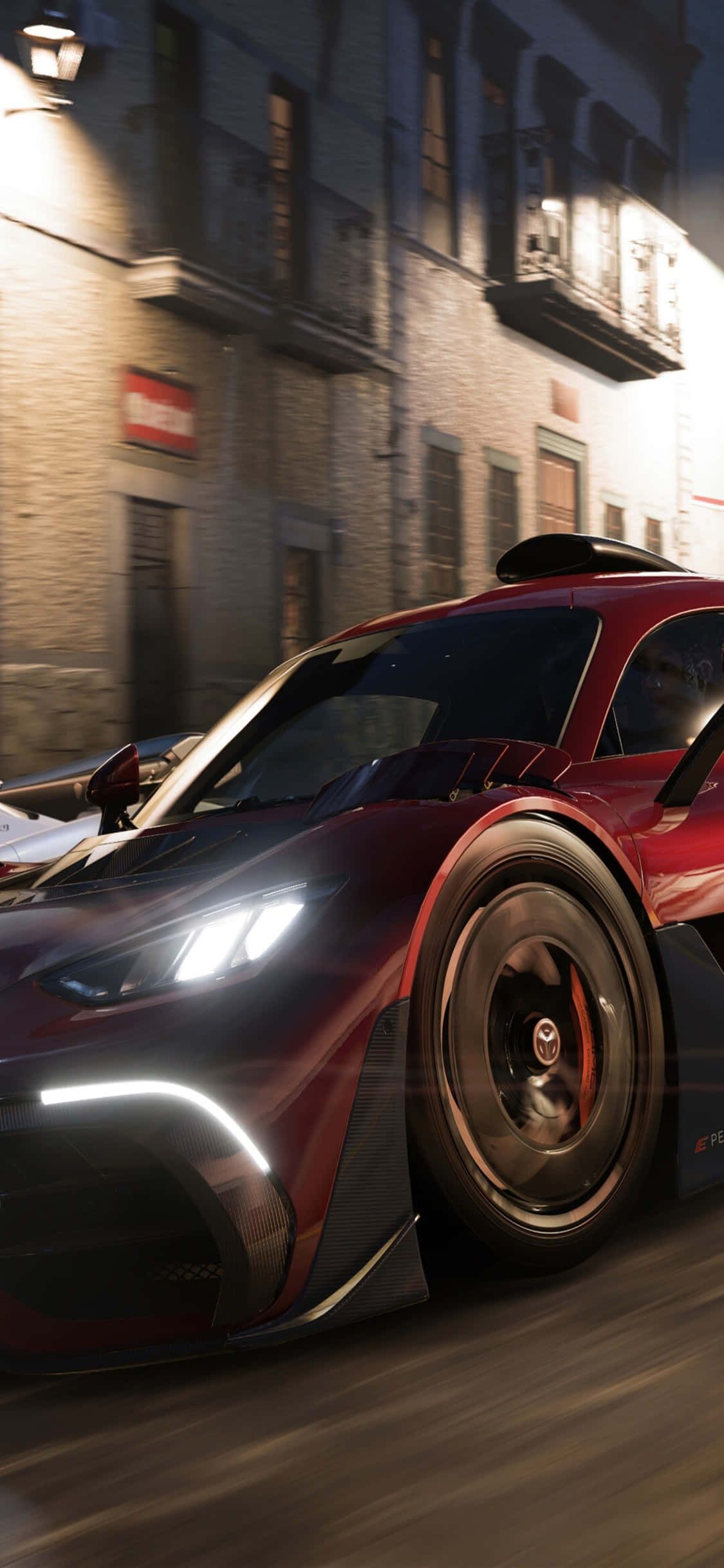 Forza 7 桌布 壁紙 — 一輛流線型紅色賽車在夜間穿過燈光昏暗的歐洲街道，帶有動態模糊和發光的車頭燈。