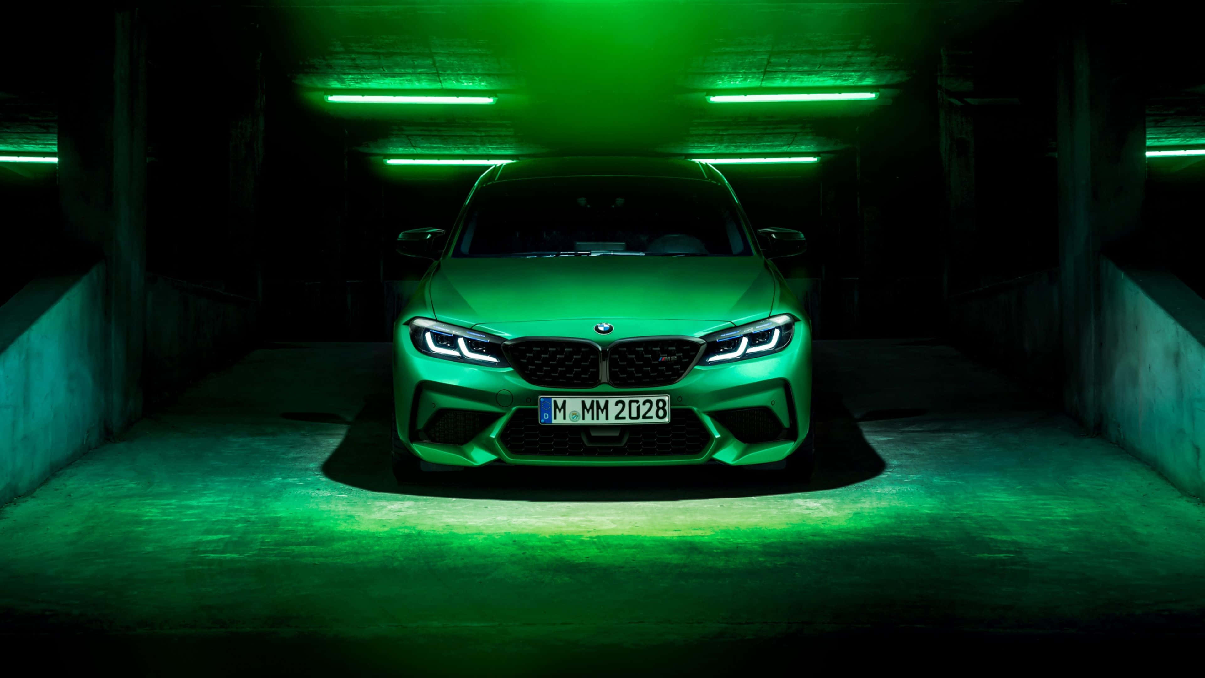 4K BMW 壁紙 桌布 壁紙 — 一輛流線型綠色BMW M2停在光線昏暗的混凝土車庫中，被天花板燈具發出的霓虹綠光淹沒。
