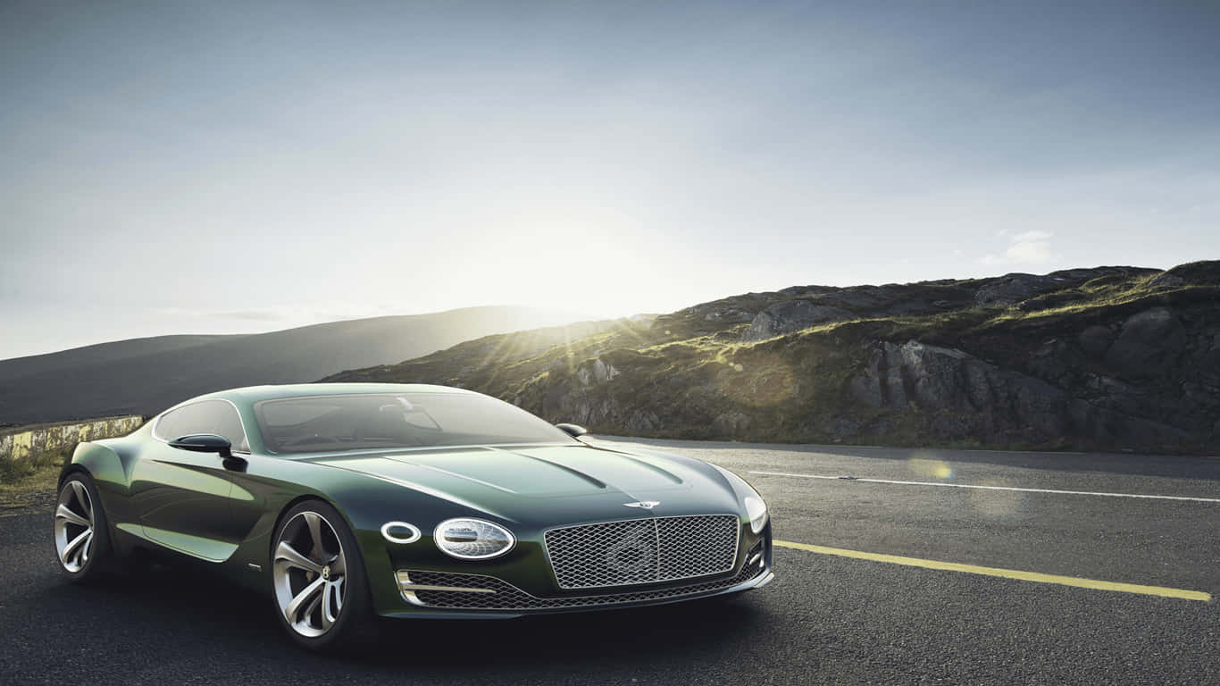 1366x768 Bentley 桌布 壁紙 — 一輛流線型綠色賓利跑車沿著蜿蜒的山路行駛，沐浴在金色的日出光芒中。