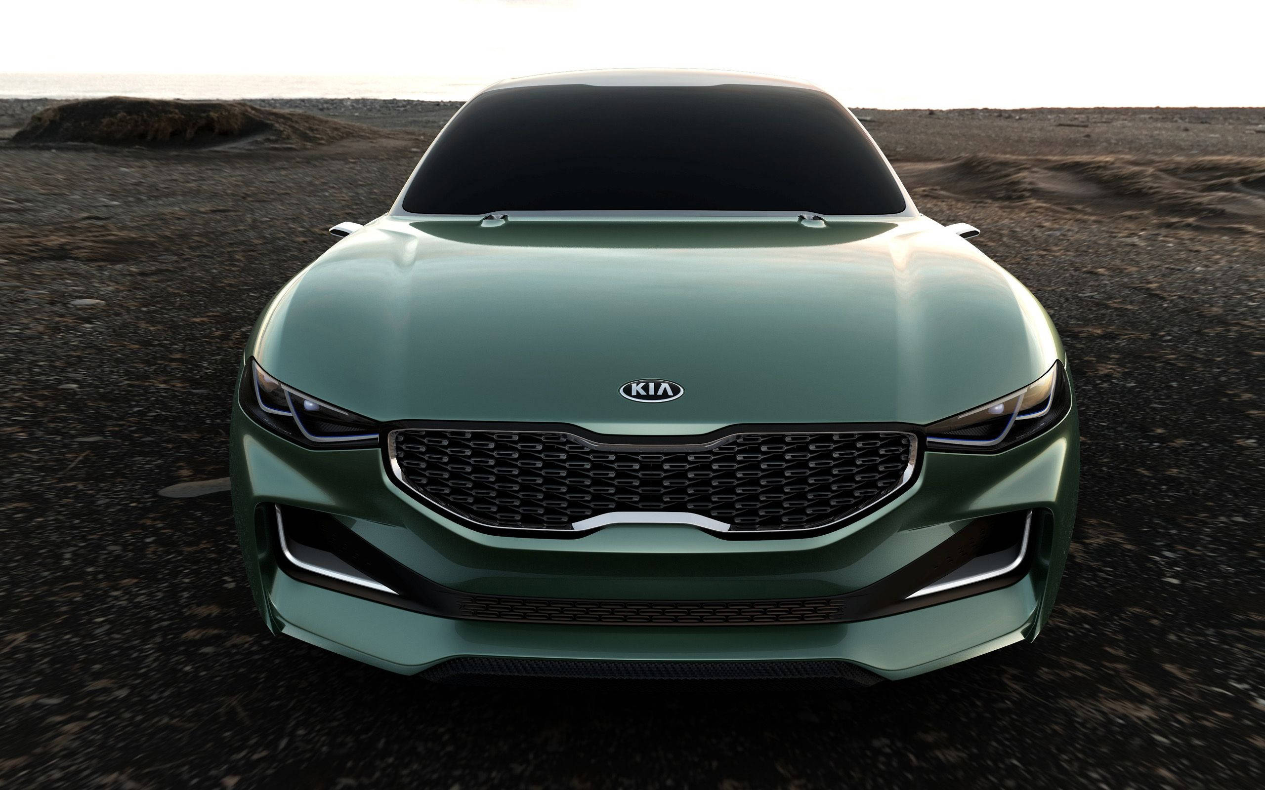 Kia 桌布 壁紙 — 一輛流線型綠色起亞概念車在荒蕪的岩石地形上，面向柔和暮色天空的前方。
