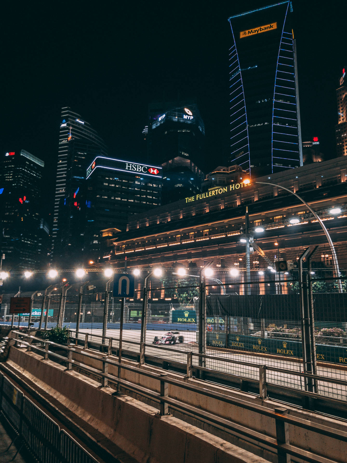 賽車在夜晚的城市賽道上飛馳，背後是燈火通明的摩天大樓。