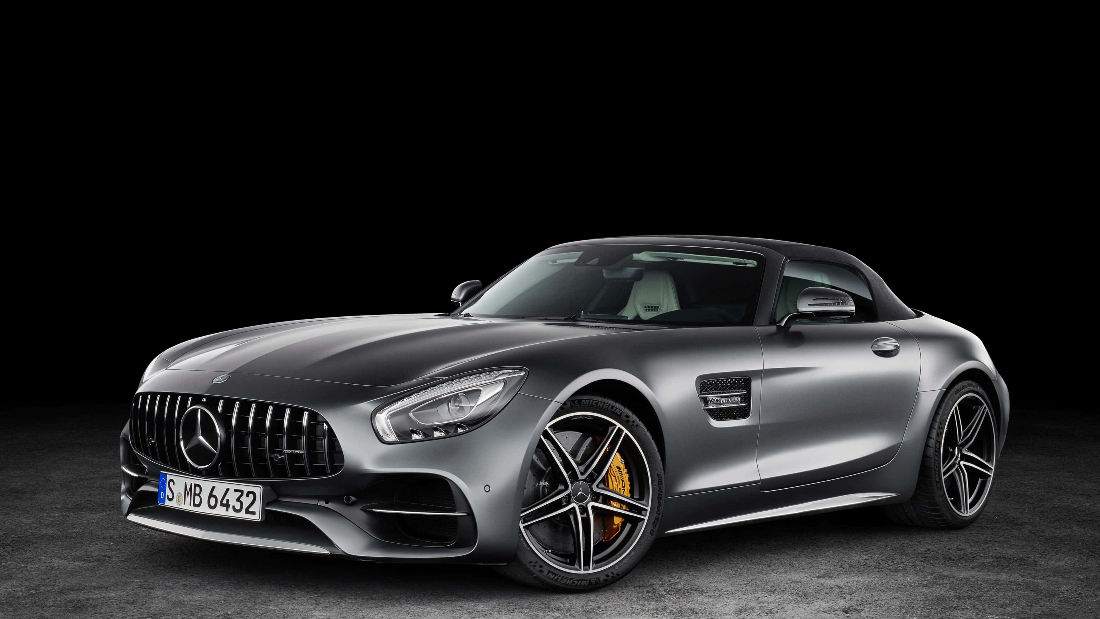 4K 奔馳壁紙 桌布 壁紙 — 一輛流線型銀色 Mercedes-AMG GT Roadster 配備黃色制動卡鉗，在純黑背景下蓄勢待發。