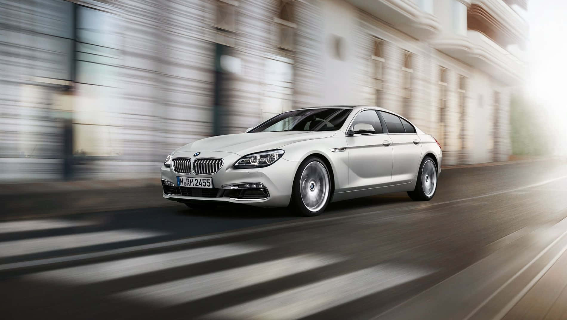 Bmw 6 Series 桌布 壁紙 — 一輛流線型銀色BMW 6系列轎車在陽光普照的都市街道上疾馳，背景建築物因動態模糊而拖曳成線。
