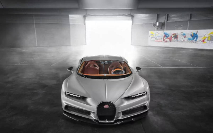 4K 桌布 壁紙 — 一輛流線型銀色Bugatti Chiron停在簡約車庫中央，背後有強烈光線湧入。