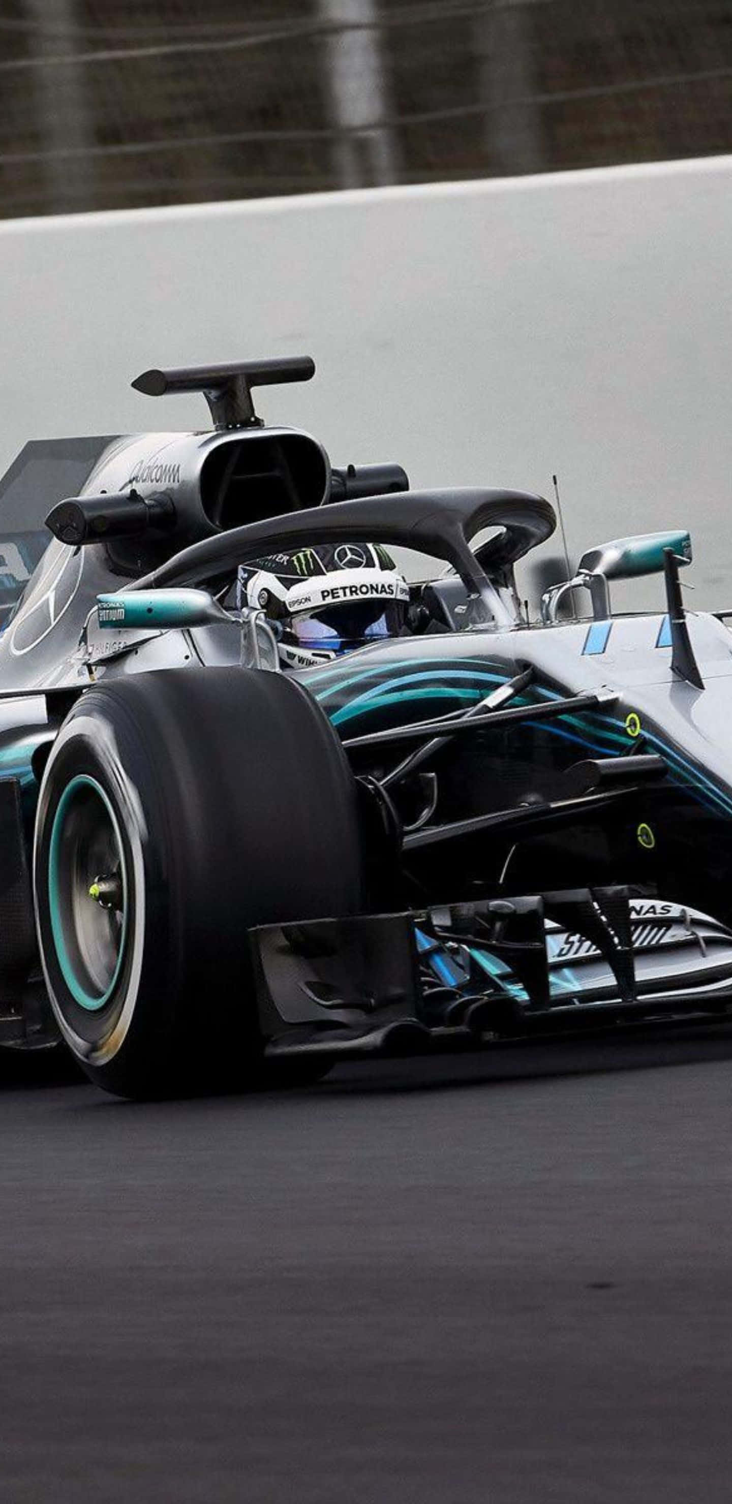 Formula 1 桌布 壁紙 — 一輛流線型銀色和藍綠色的F1賽車在潮濕的賽道上疾馳，車手戴著頭盔清晰可見。