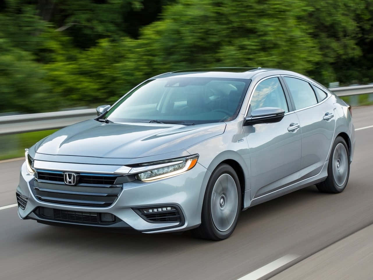 Honda Insight 桌布 壁紙 — 一輛流線型銀色本田轎車在高速公路上疾駛，背景中翠綠的樹木模糊成一片。