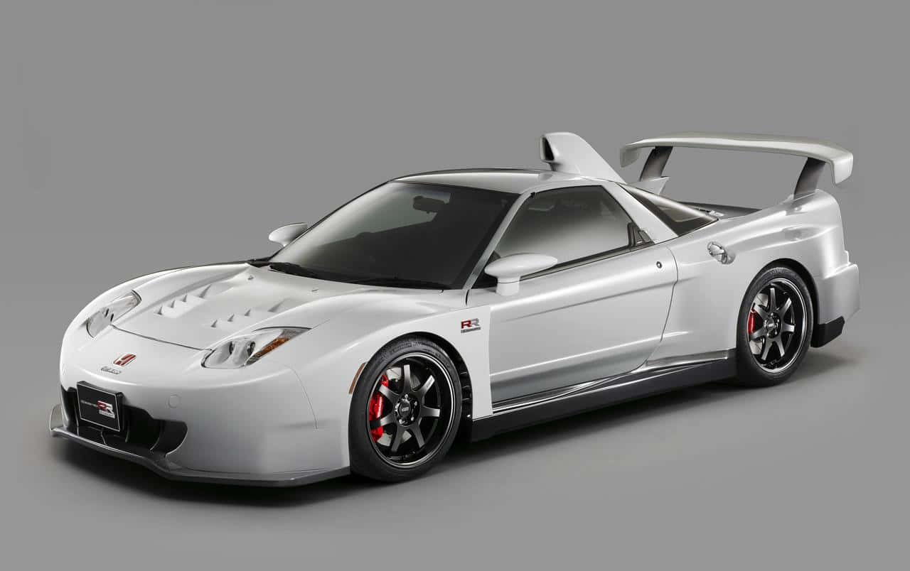 Honda Nsx 桌布 壁紙 — 一輛流線型銀色跑車，配備大型尾翼和紅色制動卡鉗，在灰色中性攝影棚背景下擺拍。