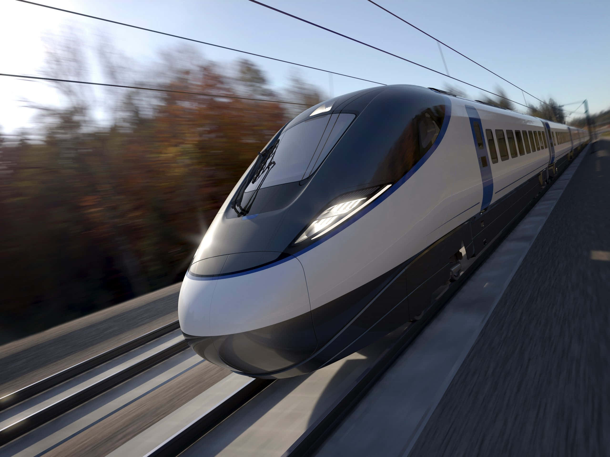 火車 桌布 壁紙 — 一輛流線型銀色高速列車在晴朗藍天下，以動態模糊效果駛過秋天的樹木。