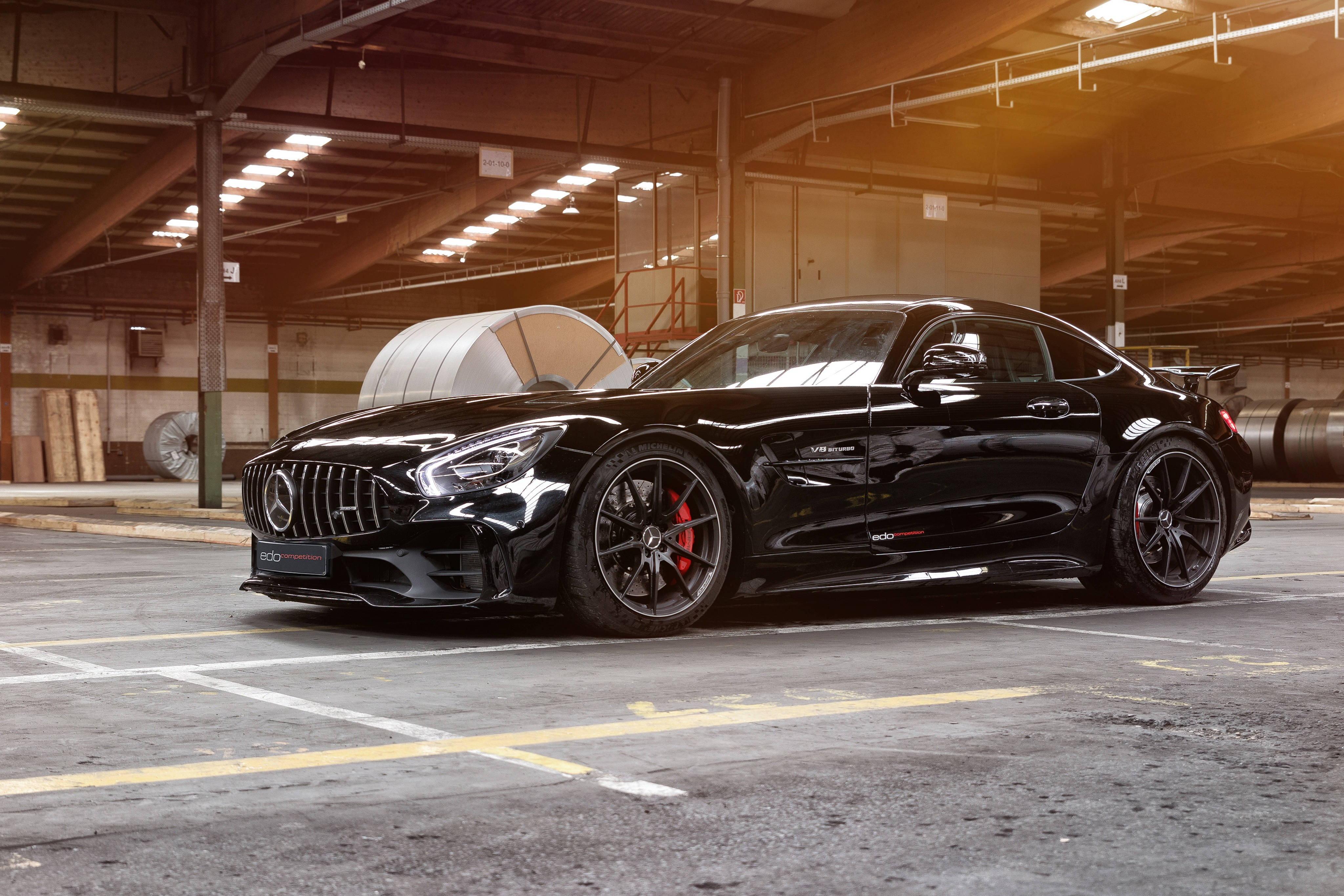 Gtr 桌布 壁紙 — 一輛流線型黑色 Mercedes-AMG GT R 跑車在寬敞的倉庫車庫中，於溫暖的工業燈光下閃閃發光。