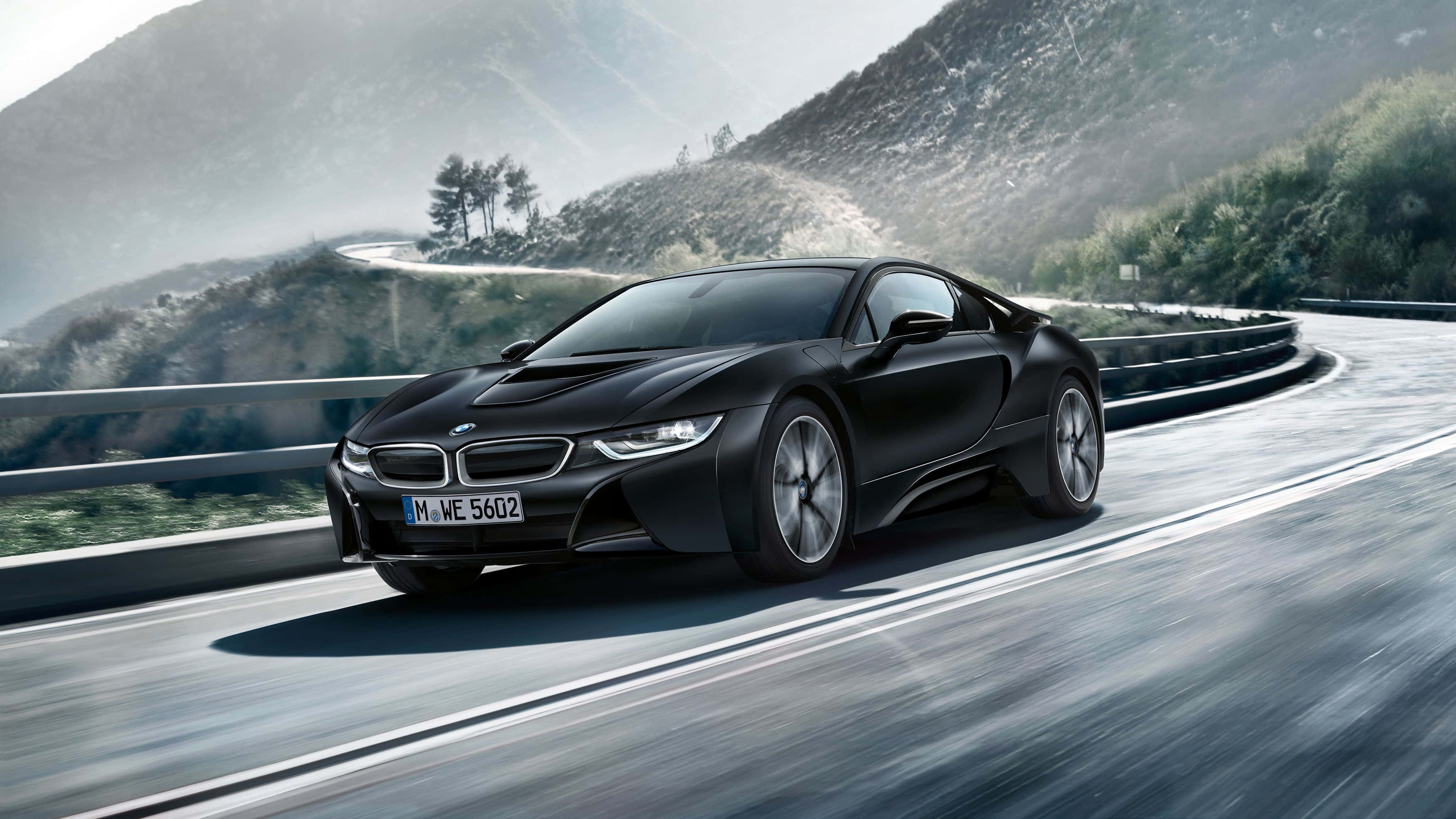 Bmw Cars 桌布 壁紙 — 一輛流線型黑色BMW i8跑車沿著蜿蜒的山路高速行駛，背景有模糊的動感和霧氣繚繞的山峰。