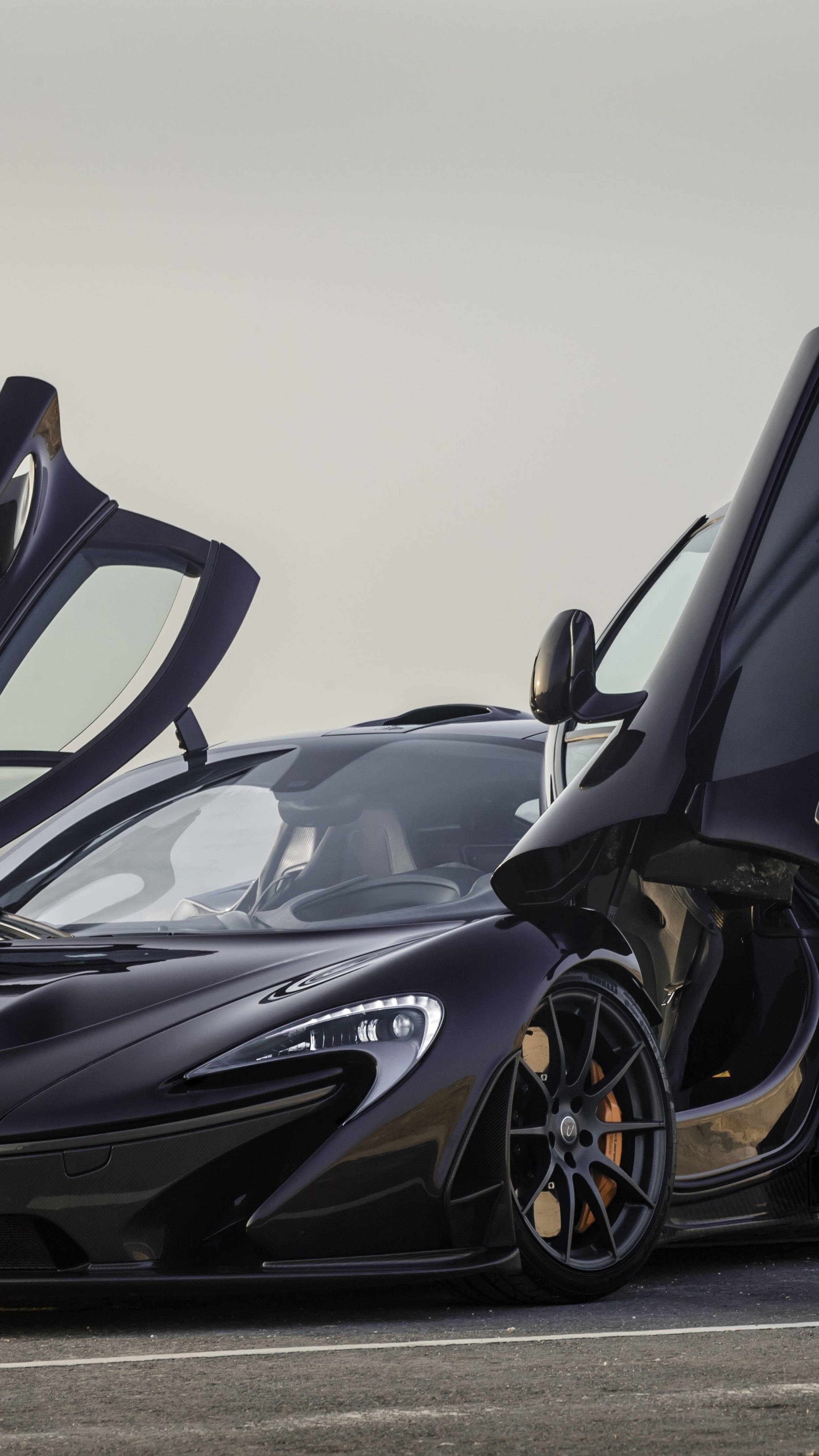 Luxury 桌布 壁紙 — 一輛流線型黑色McLaren跑車，在陰天的天氣下，在鋪砌的路面上打開鷗翼車門。