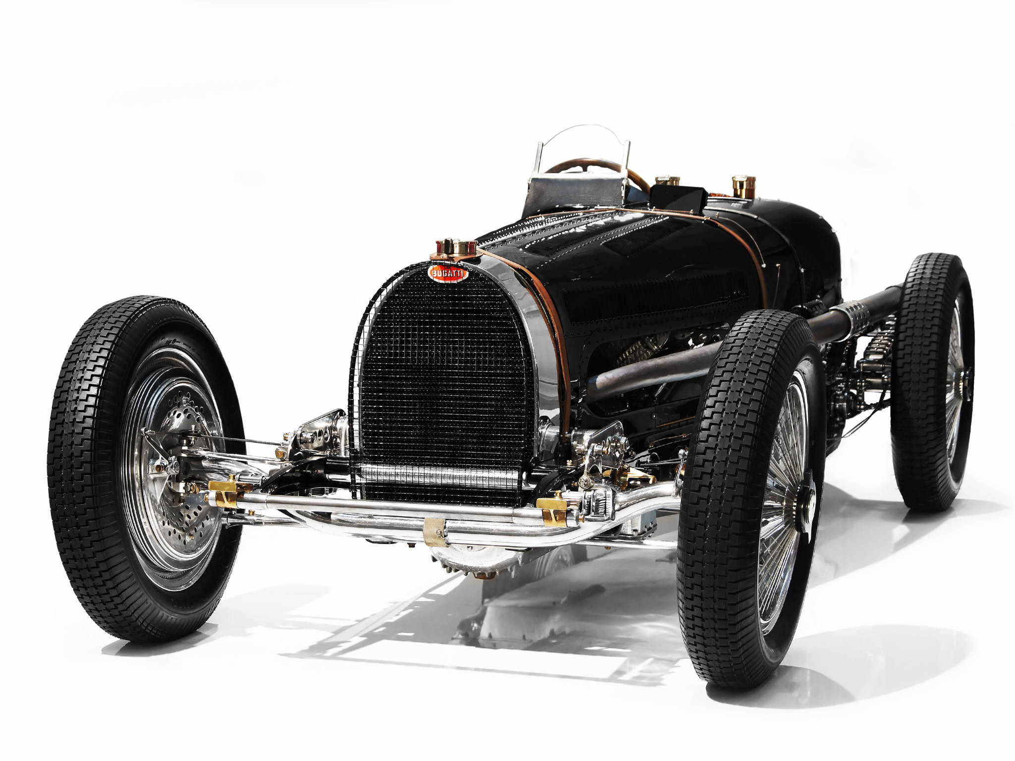 bugatti iPhone 桌布 壁紙 — 一輛流線型黑色復古Bugatti賽車，帶有鍍鉻裝飾和裸露的機械結構，矗立在純白色工作室背景前。