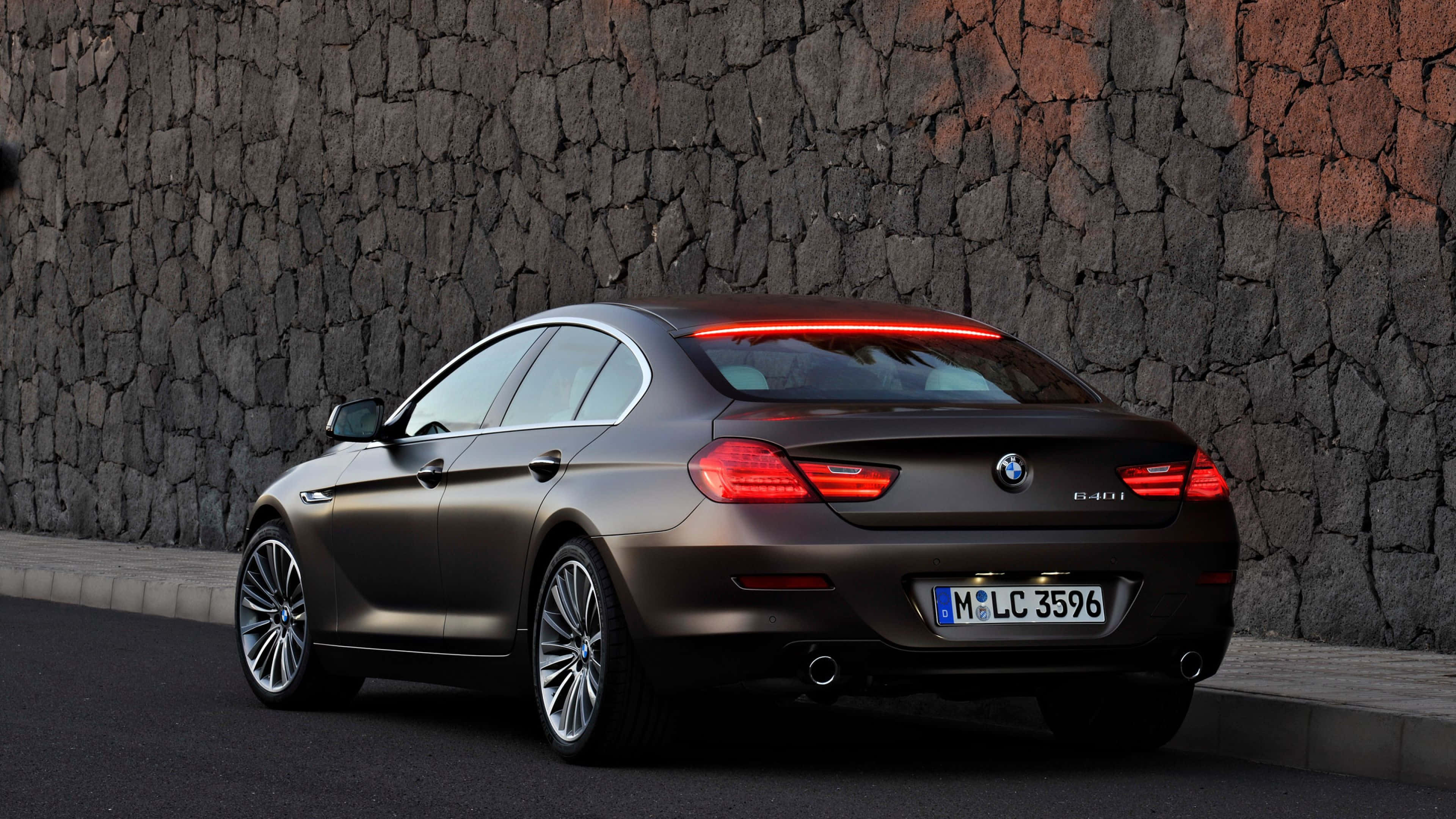 Bmw 6 Series 桌布 壁紙 — 一輛消光棕色BMW 6系列Gran Coupe停在粗獷石牆旁，紅色尾燈發亮。
