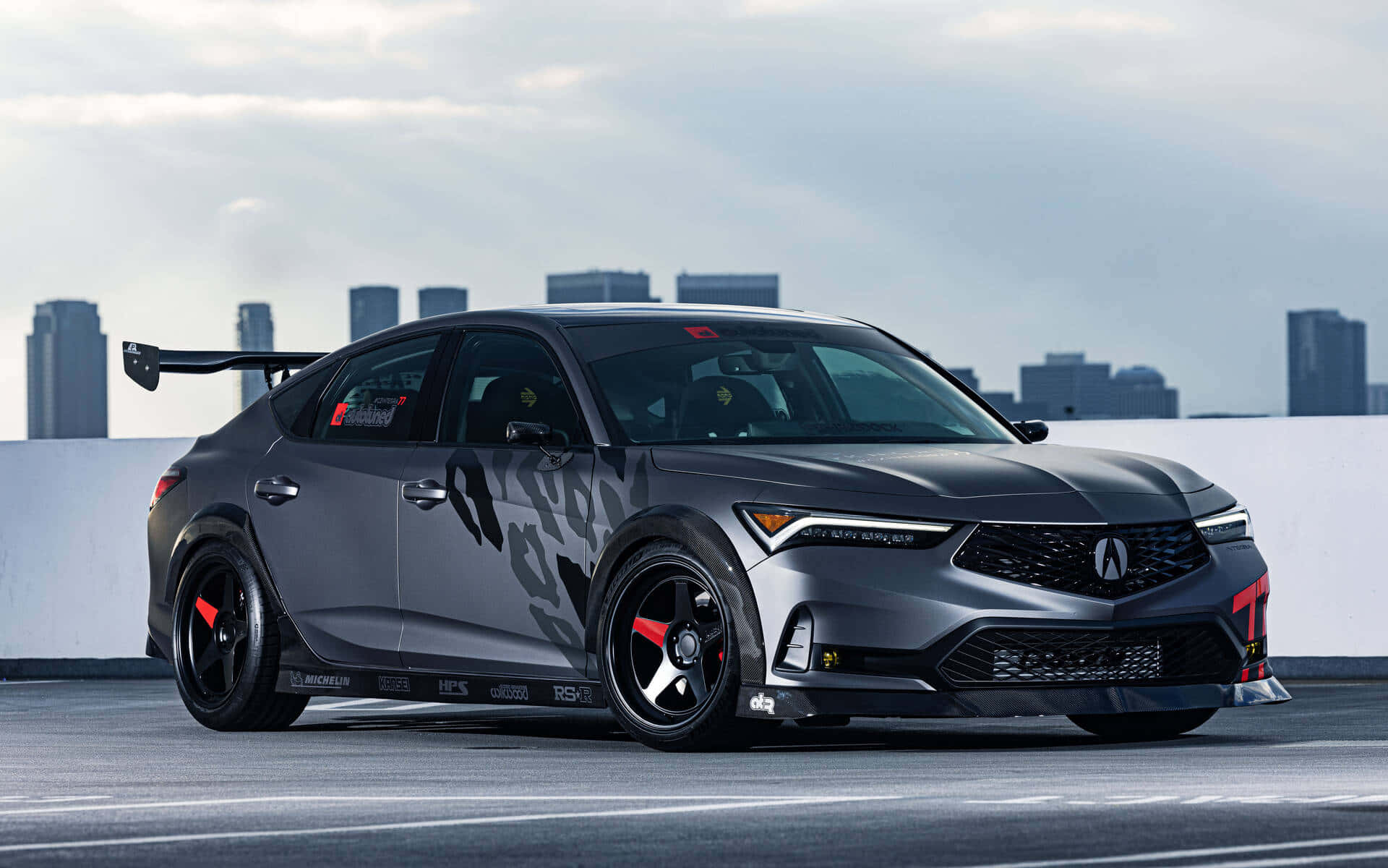 Acura Integra 桌布 壁紙 — 一輛消光灰色Acura NSX賽車，帶有紅色點綴和大型後擾流板，停放在俯瞰城市天際線的屋頂上。