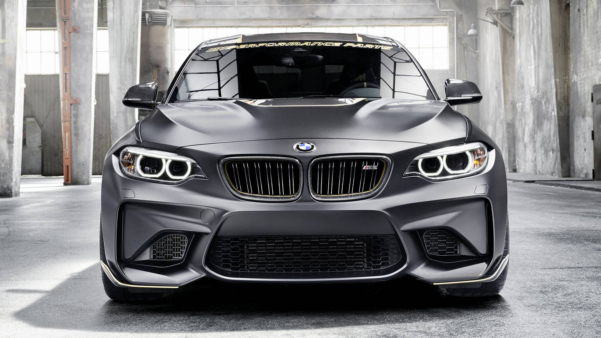 m 桌布 壁紙 — 一輛消光灰色BMW M2跑車搭配金色飾邊停放在混凝土工業倉庫內。