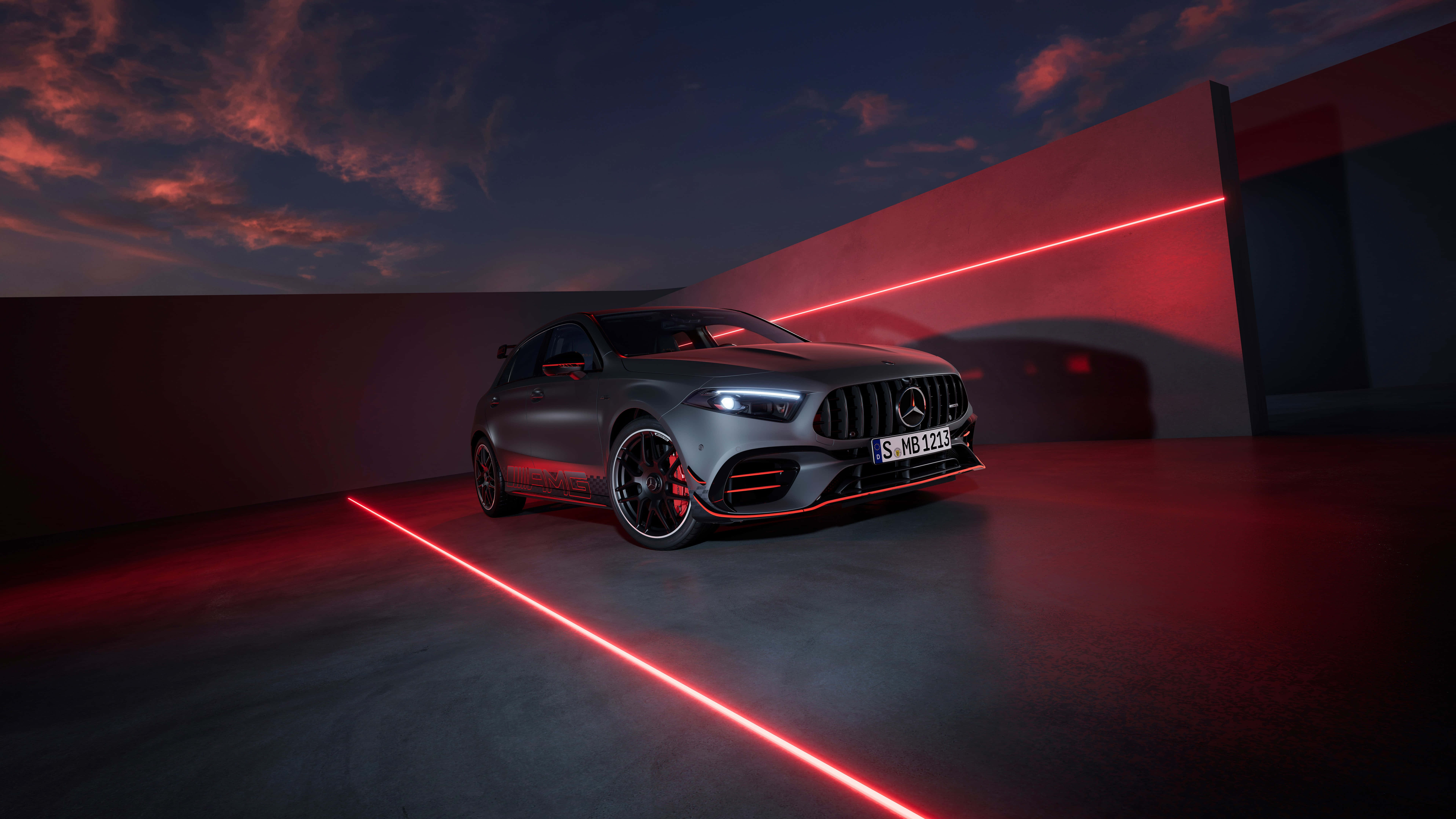 8K 桌布 壁紙 — 一輛消光灰色的 Mercedes-AMG A45 S 跑車在戲劇性的紅色雷射燈光下，映襯著暮色天空閃耀。
