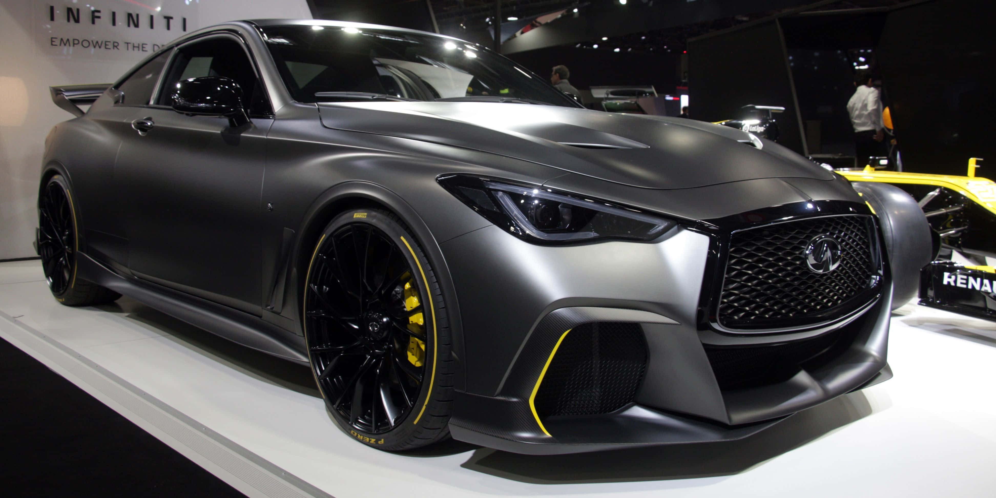 Infiniti Q60 桌布 壁紙 — 一輛消光灰色的Infiniti跑車，車輪和飾條上帶有醒目的黃色點綴，在車展的白色平台上展示。
