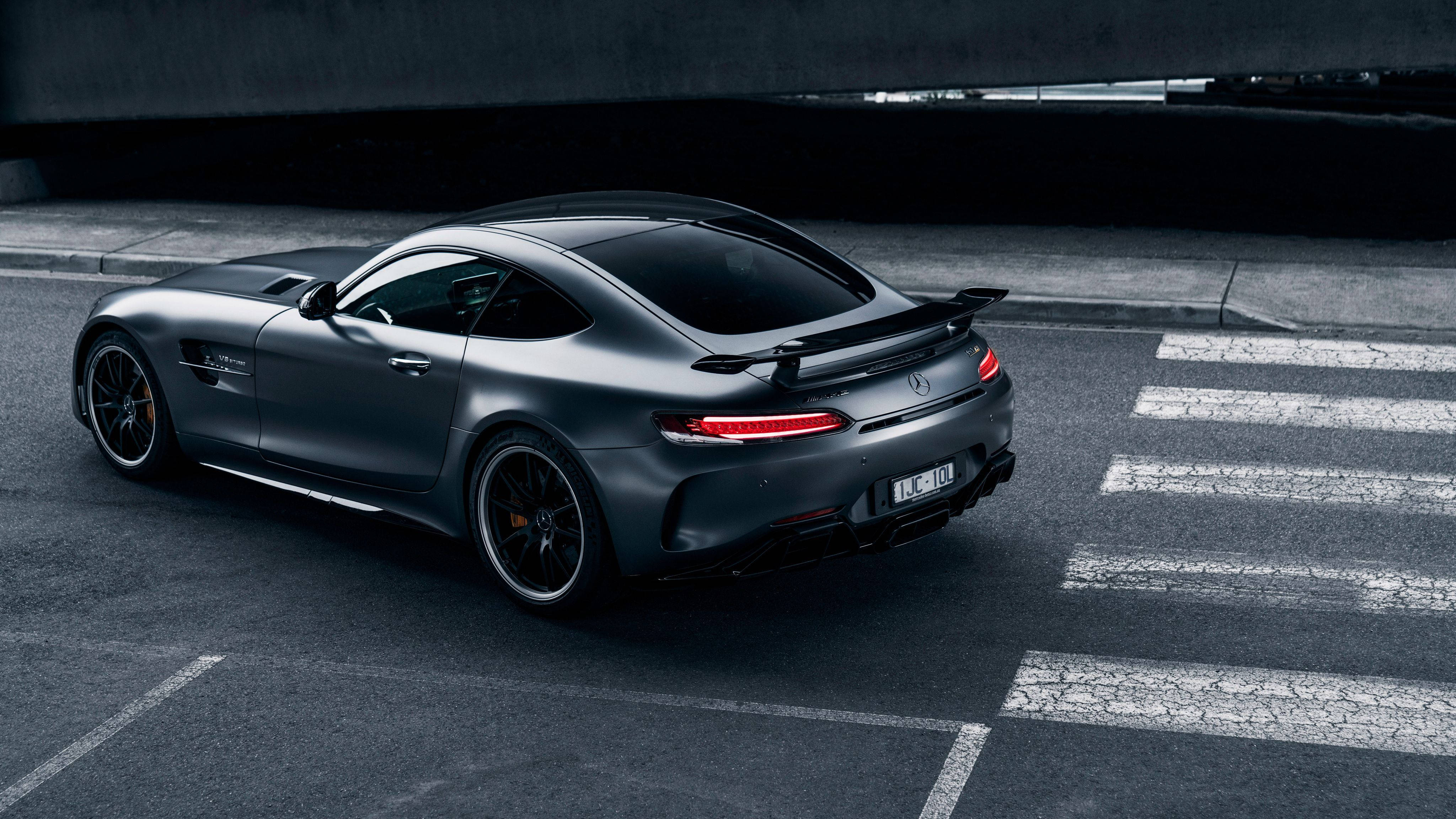 Mercedes 桌布 壁紙 — 一輛消光黑色的 Mercedes-AMG GT R 跑車停放在天橋下龜裂的柏油路上，紅色尾燈發光。