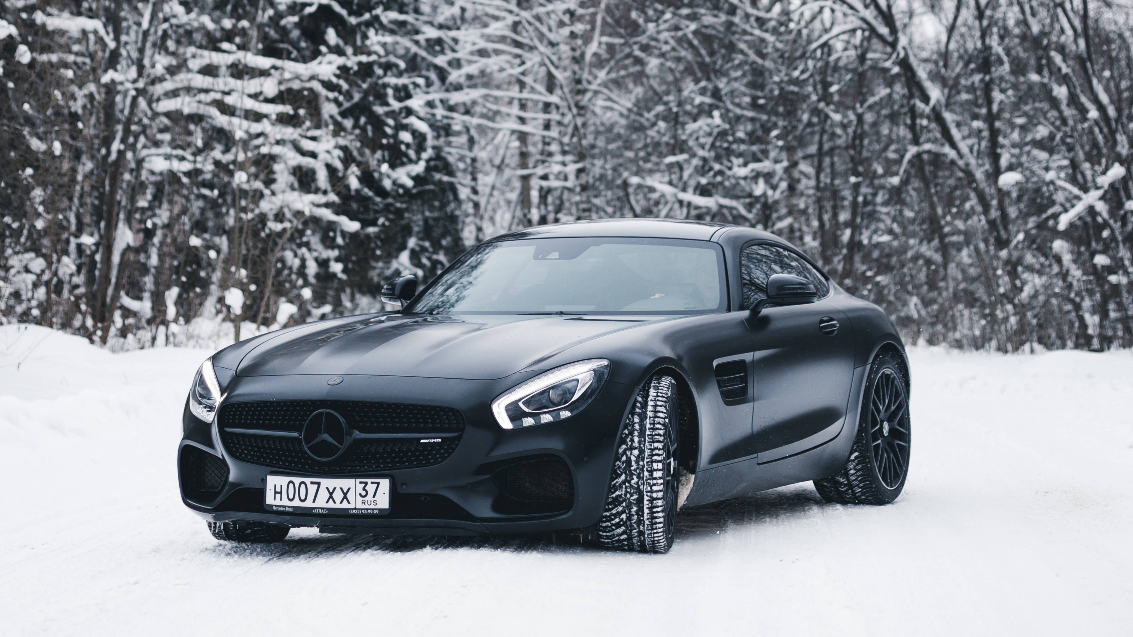 4K 奔馳壁紙 桌布 壁紙 — 一輛消光黑色的Mercedes-AMG GT跑車停在深雪中，背景是積雪的樹木。