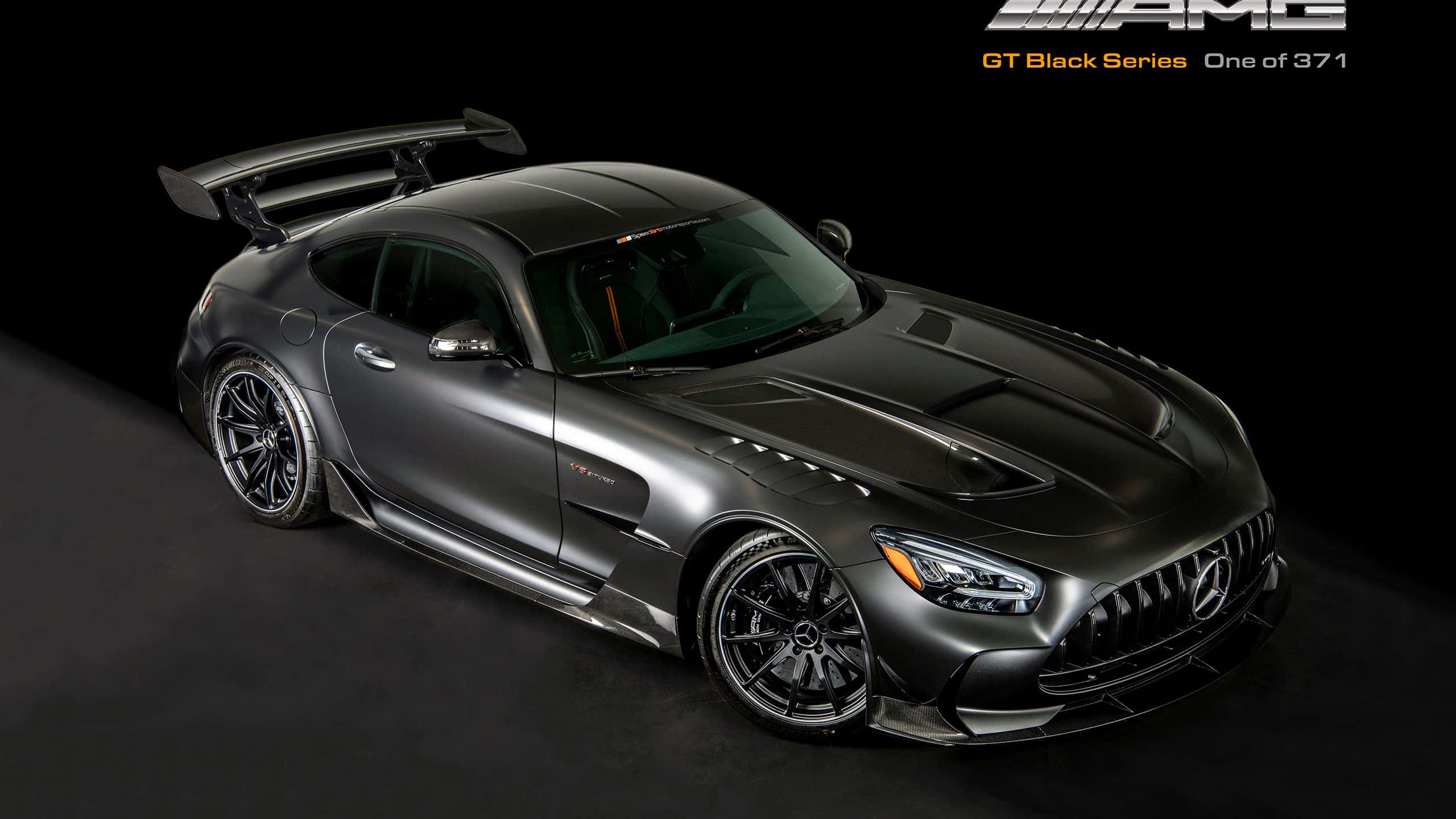 Mercedes Gts 桌布 壁紙 — 一輛消光黑色的Mercedes-AMG GT Black Series跑車，配備大型尾翼和激進的空氣動力學設計，在攝影棚內以深色背景拍攝。