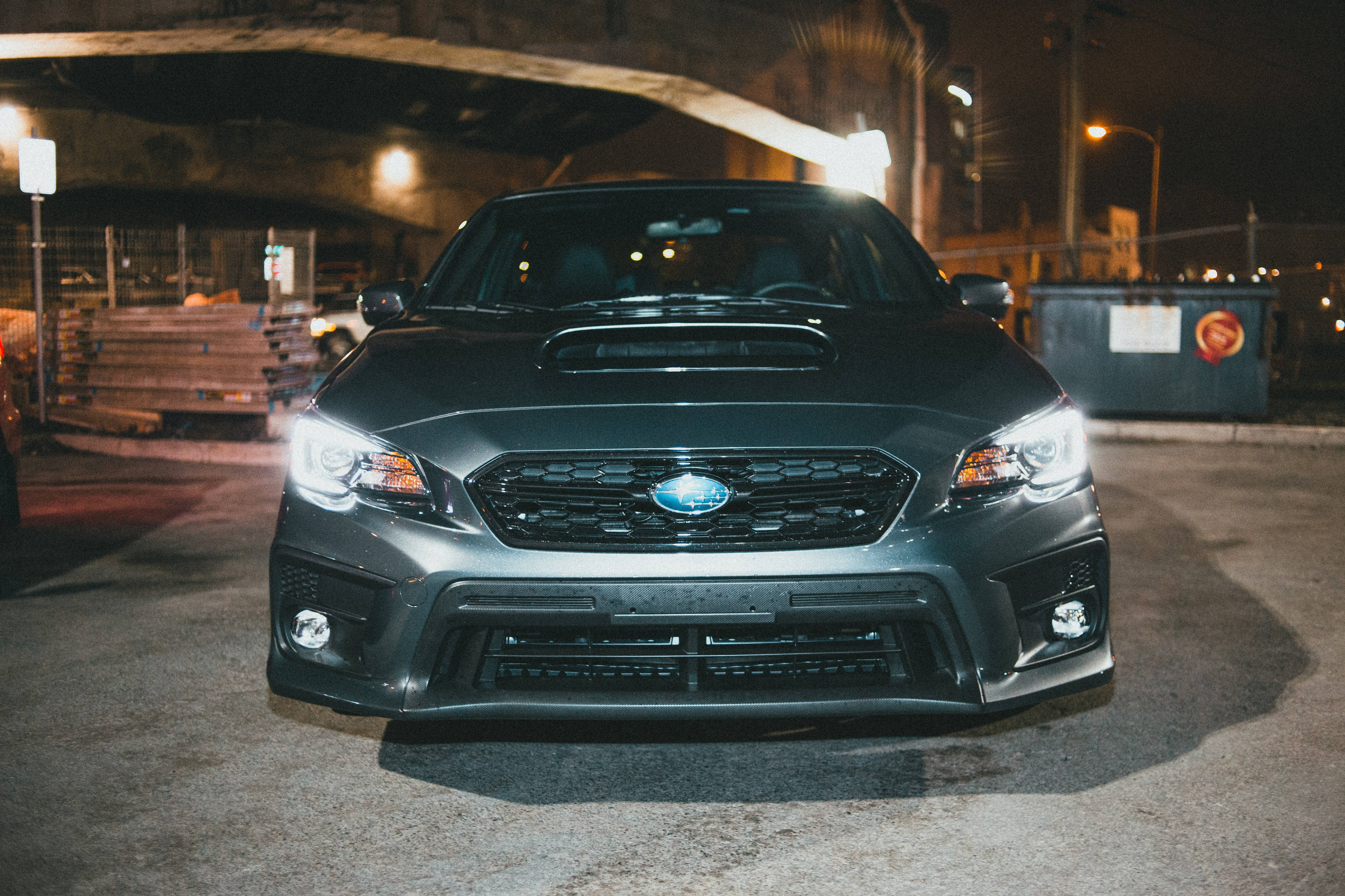 昴 桌布 壁紙 — 一輛消光黑色的Subaru WRX STI在夜晚的骯髒城市地下道中，在街燈下閃閃發光。