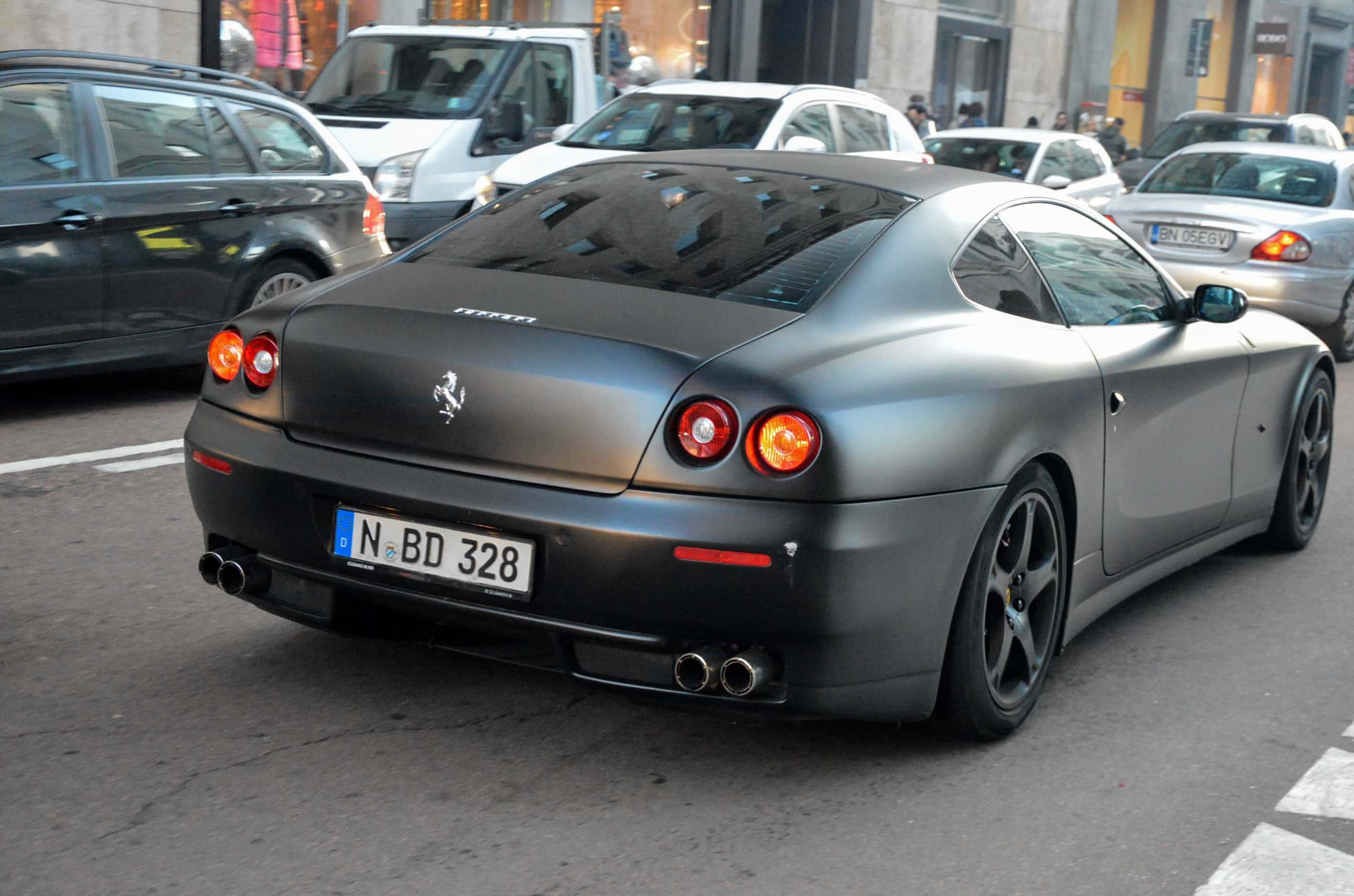 Ferrari 612 Scaglietti 桌布 壁紙 — 一輛消光黑色的法拉利612 Superamerica停在繁忙的城市街道上，紅色尾燈閃閃發光。