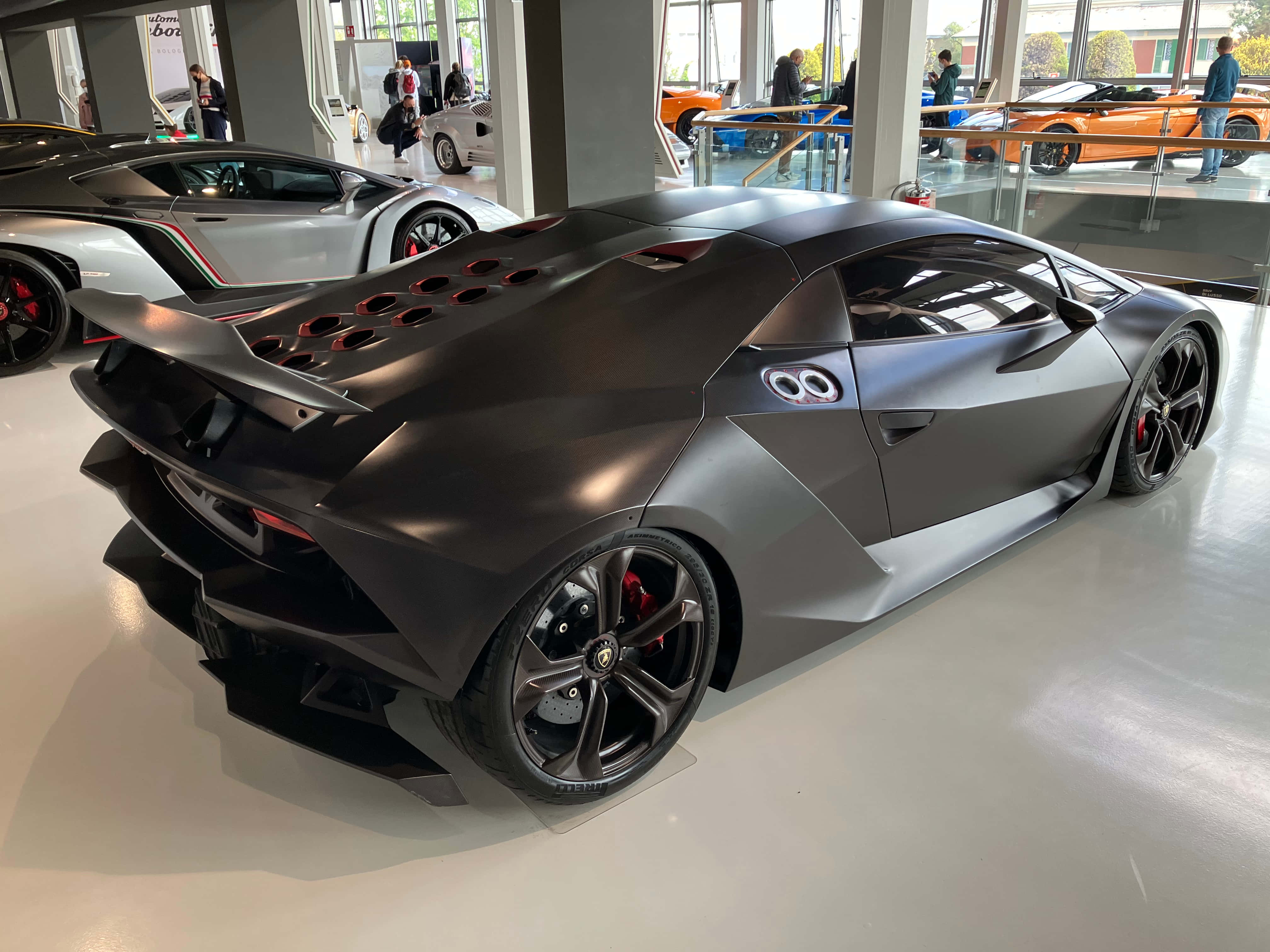 Lamborghini Sesto Elemento 桌布 壁紙 — 一輛消光黑色的藍寶堅尼搭配紅色煞車卡鉗，在明亮的燈光下於時尚的汽車展示間中閃耀。