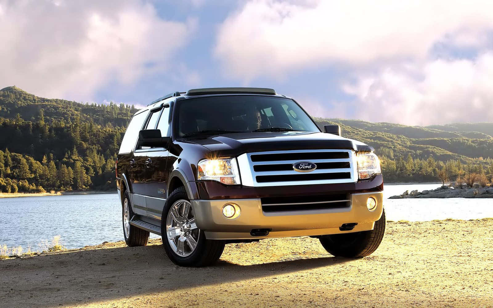 Ford Expedition 桌布 壁紙 — 一輛深棗紅色的福特 Expedition SUV 停泊在湖岸邊，背景是山脈和樹木，天空多雲。