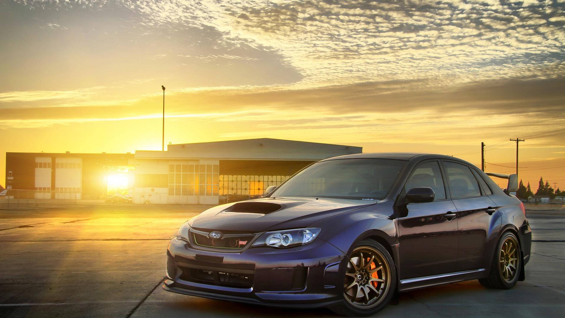 昴 桌布 壁紙 — 一輛深紫色Subaru WRX STI停在混凝土上，金色夕陽光芒在現代建築後方閃耀。