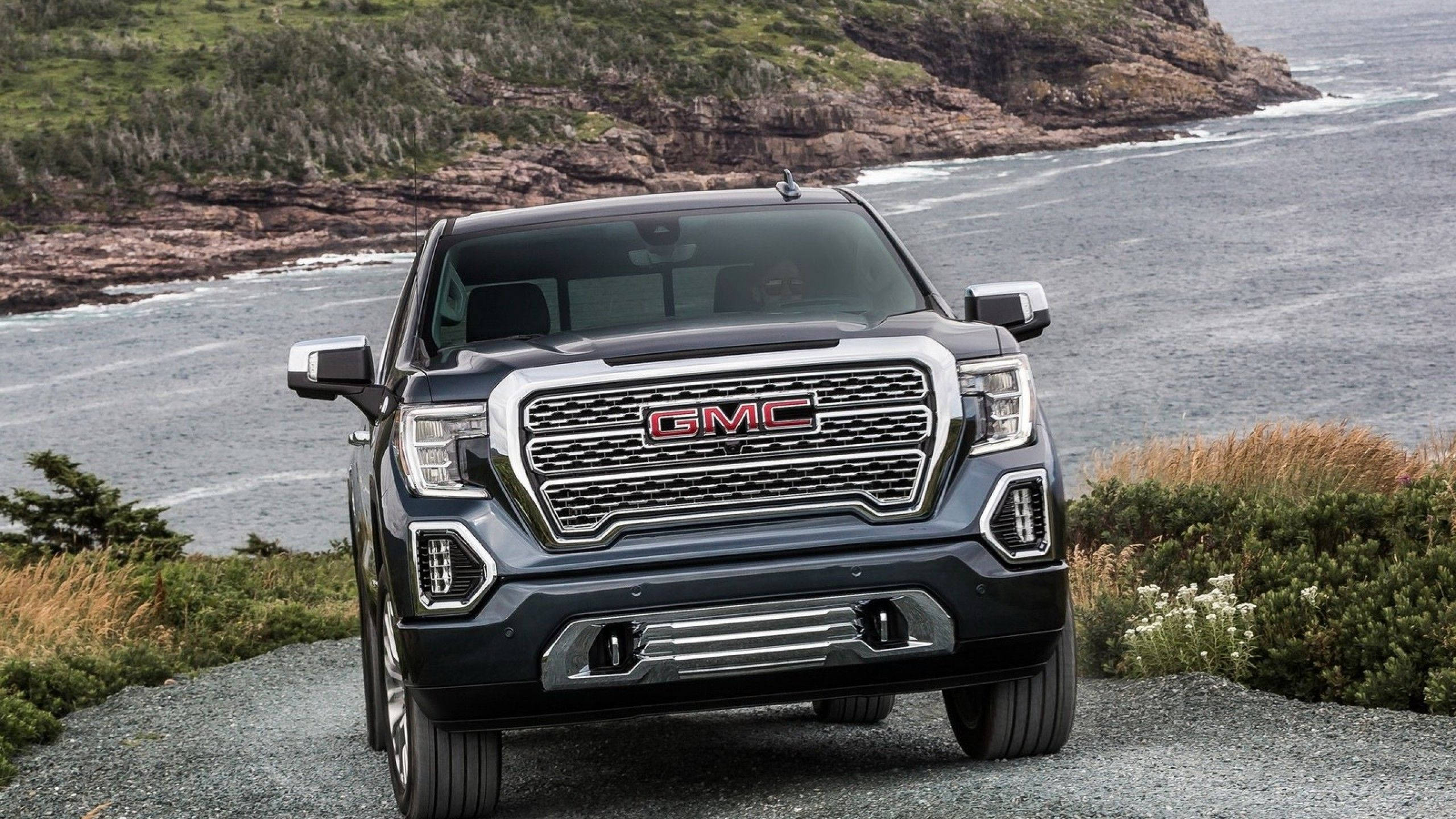Gmc 桌布 壁紙 — 一輛深色GMC卡車停泊在岩石海岸小徑上，身後海浪拍打懸崖。