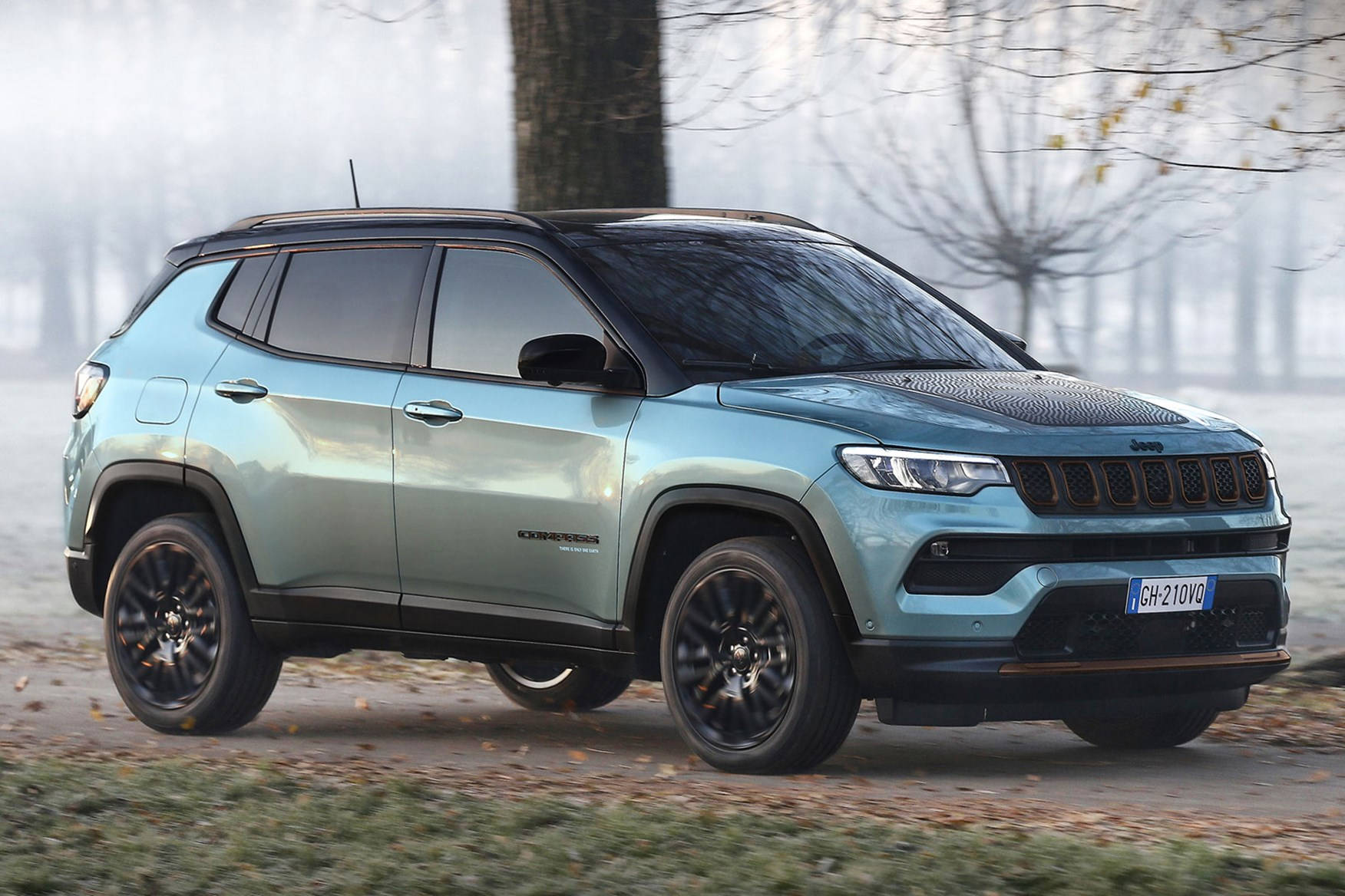 森林 桌布 壁紙 — 一輛淺藍色Jeep Compass SUV停泊在霧氣瀰漫的秋日路邊，周圍有光禿的樹木和落葉。