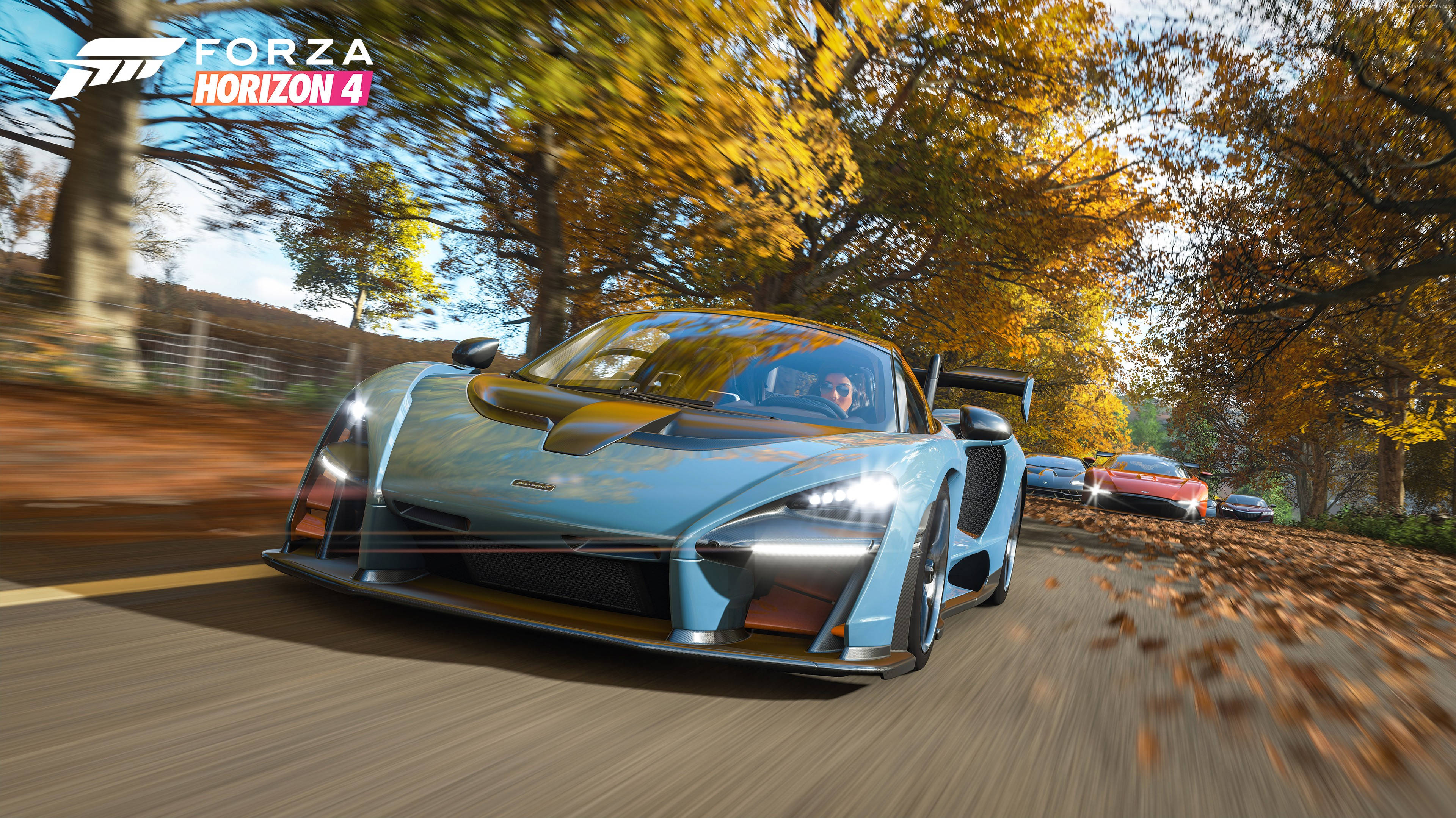 Forza Gaming 桌布 壁紙 — 一輛淺藍色McLaren超級跑車在充滿活力的秋日森林中疾馳，金色樹葉在車輪周圍旋轉。
