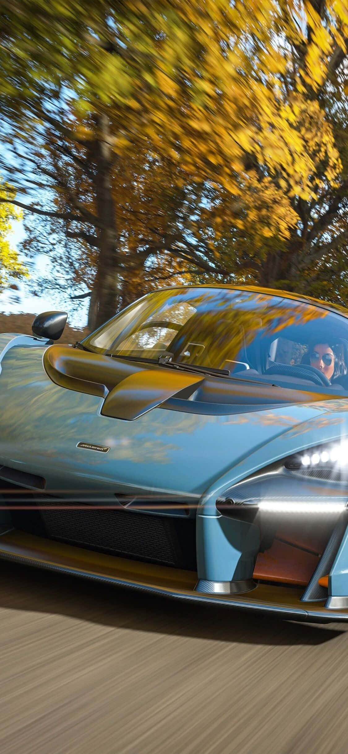 電玩遊戲 桌布 壁紙 — 一輛淺藍色McLaren超級跑車在模糊的動感和鮮豔的樹葉中穿過金色的秋日森林。