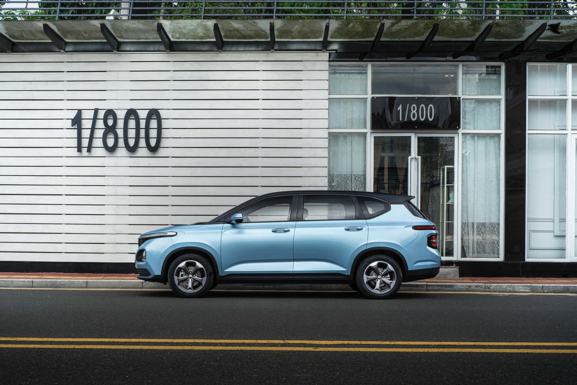 Baojun 桌布 壁紙 — 一輛淺藍色SUV停在一條街上，旁邊是一棟現代建築，其白色板條牆上有「1/800」標誌。