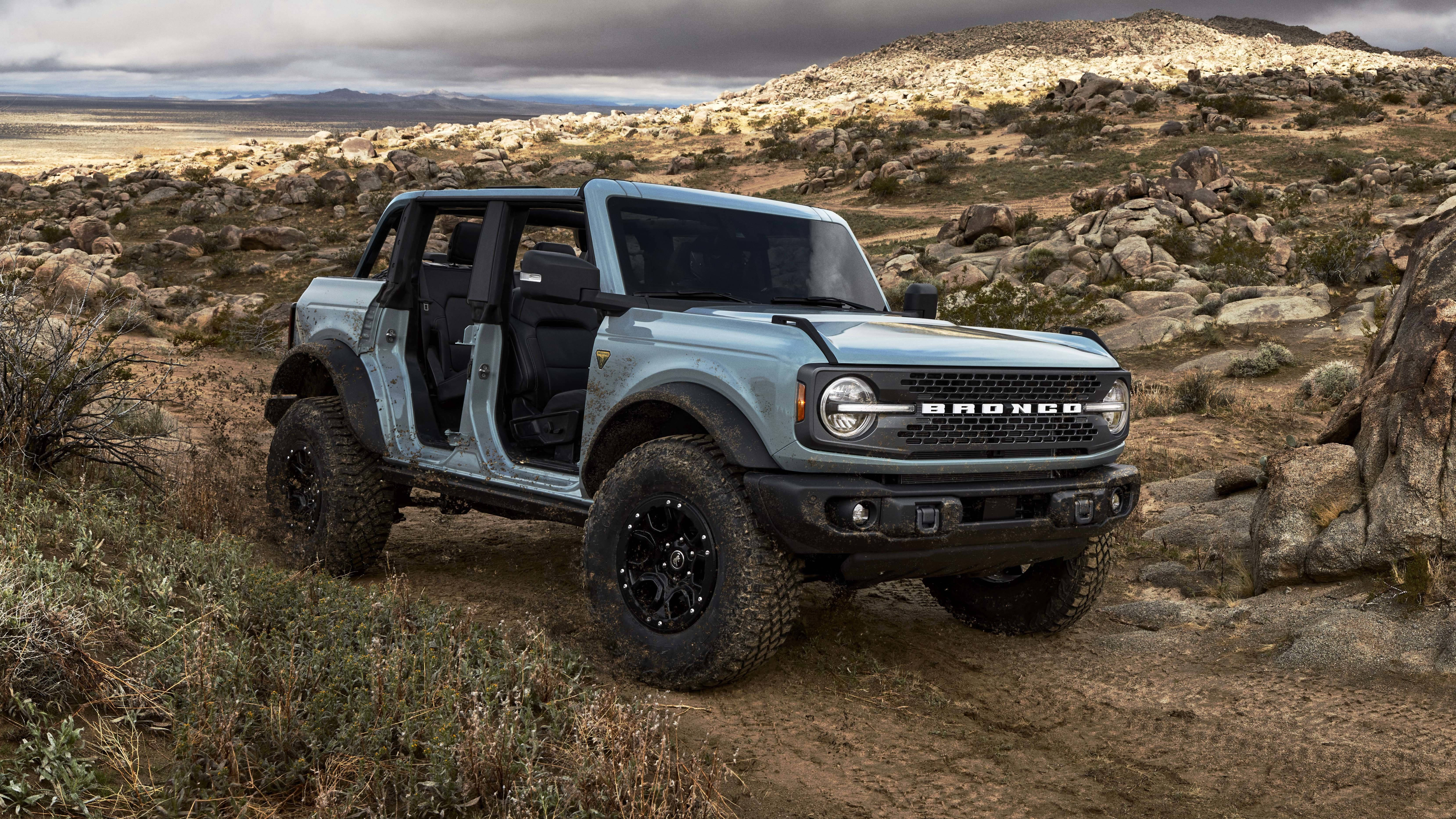 Ford Bronco 桌布 壁紙 — 一輛淺藍色福特Bronco打開車門，在陰天的岩石沙漠小徑上堅固地停泊。