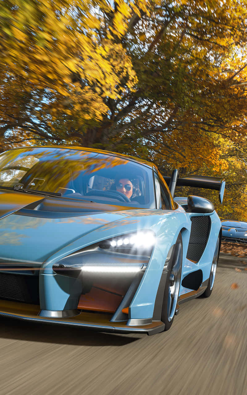 Android Forza Horizon 4 桌布 壁紙 — 一輛淺藍色超級跑車在模糊的動感和鮮豔的秋葉中，飛馳穿過金色的秋日森林。