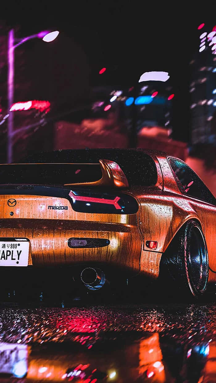 JDM 桌布 壁紙 — 一輛濕漉漉的金色馬自達RX-7跑車在夜晚的霓虹城市燈光下閃閃發光，倒影在雨水濕滑的路面上舞動。