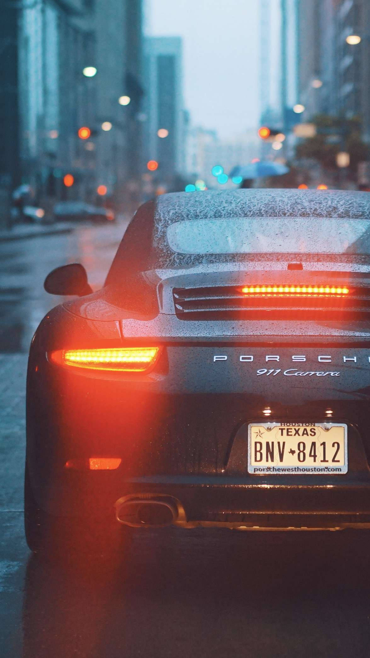 在雨城市街道上停泊的黑色保時捷911 Carrera，紅色尾燈。 — 保時捷 GIF 壁紙
