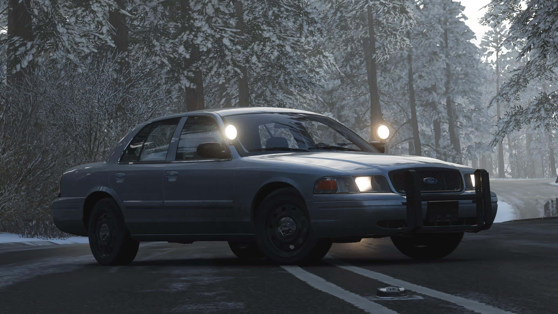Ford Crown Victoria 桌布 壁紙 — 一輛灰色警用轎車亮著頭燈，在黃昏時分駛過白雪覆蓋的森林。