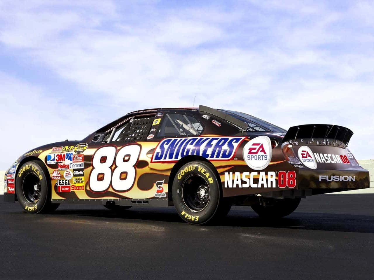 nascar 桌布 壁紙 — 一輛由Snickers贊助的NASCAR賽車88號在明亮的日光下在賽道上閃閃發光，帶有贊助商標誌和醒目的火焰圖案。