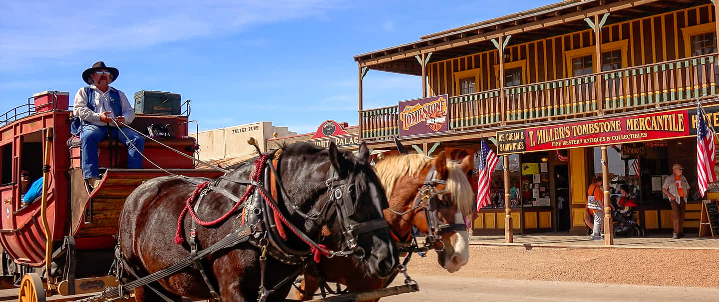 Old Western 桌布 壁紙 — 一輛由兩匹馬拉動的驛馬車停在復古西部商店門前，天空湛藍清澈。