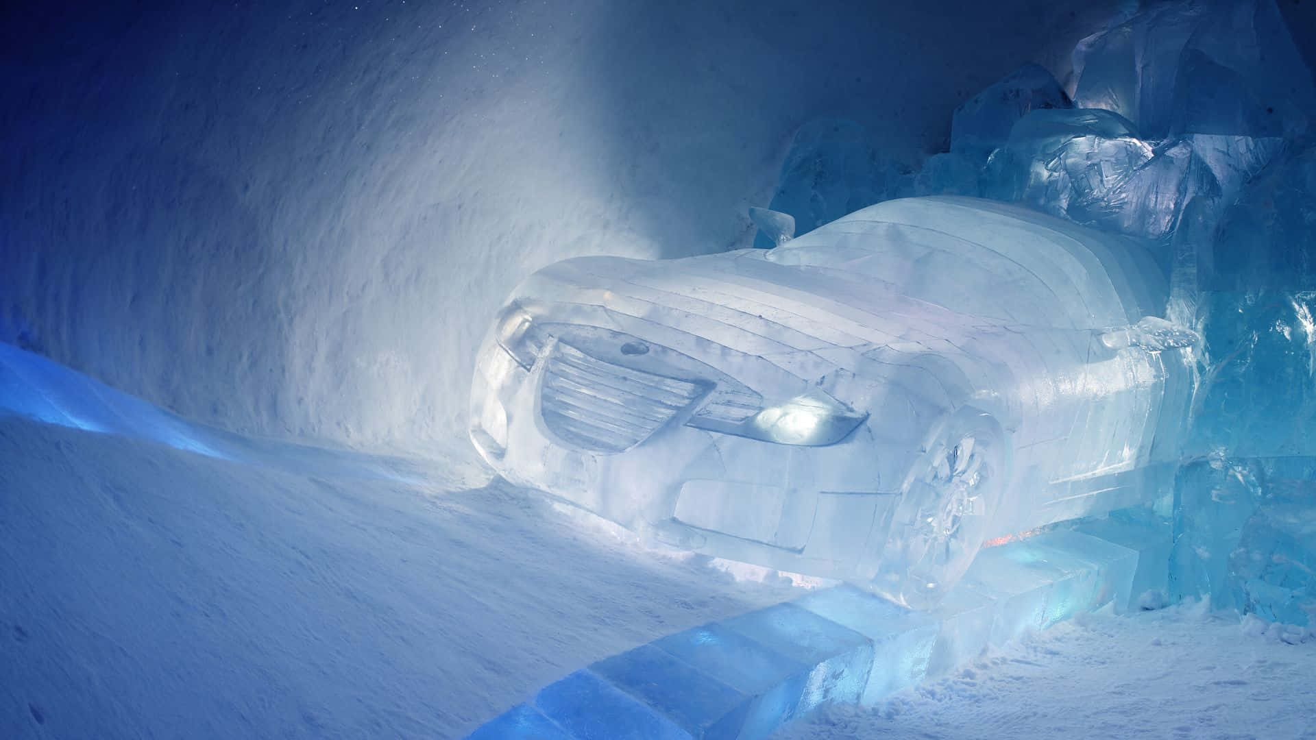 Ice Hotel 桌布 壁紙 — 一輛由冰雕成的時尚汽車在雪洞內藍光下閃耀。